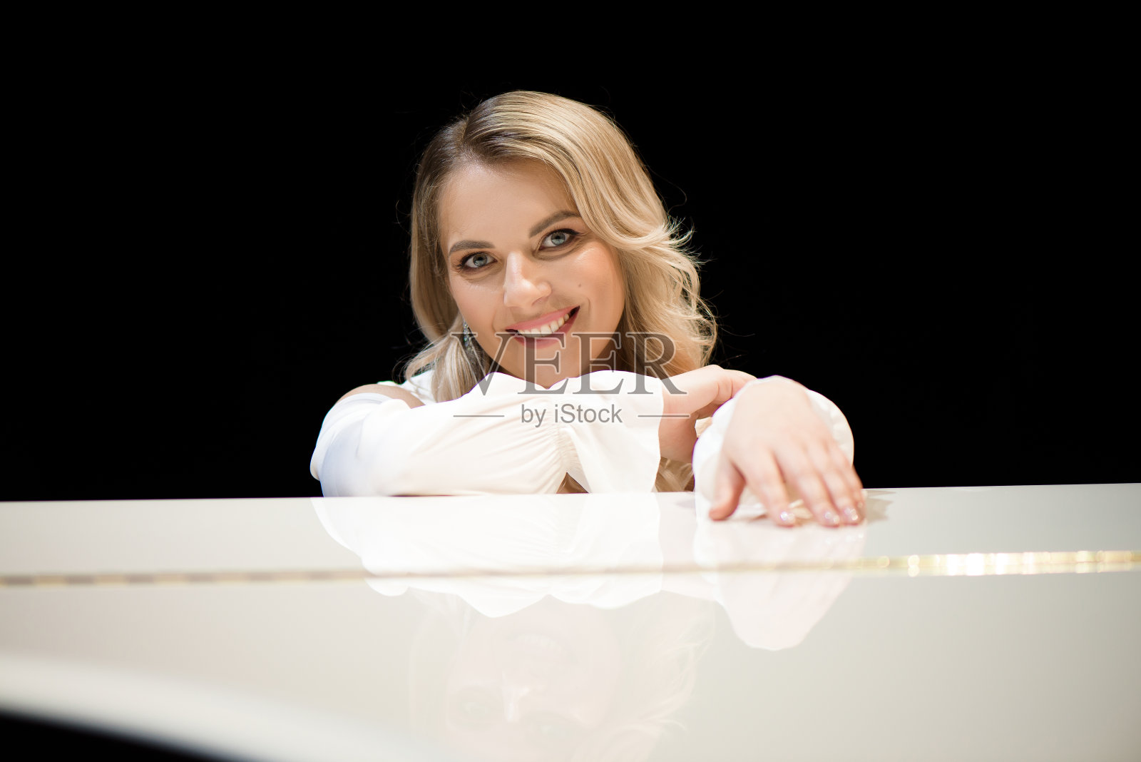 钢琴师在舞台上白色钢琴旁摆姿势照片摄影图片