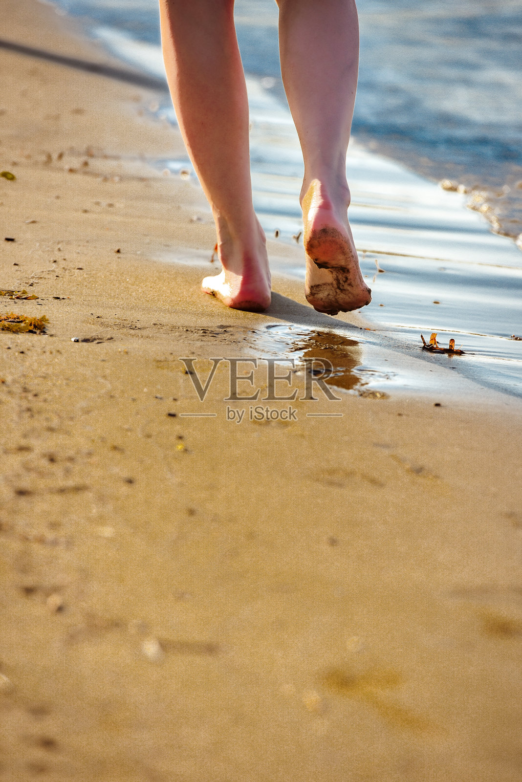 日落时分,女人在海滩上散步的小路照片摄影图片
