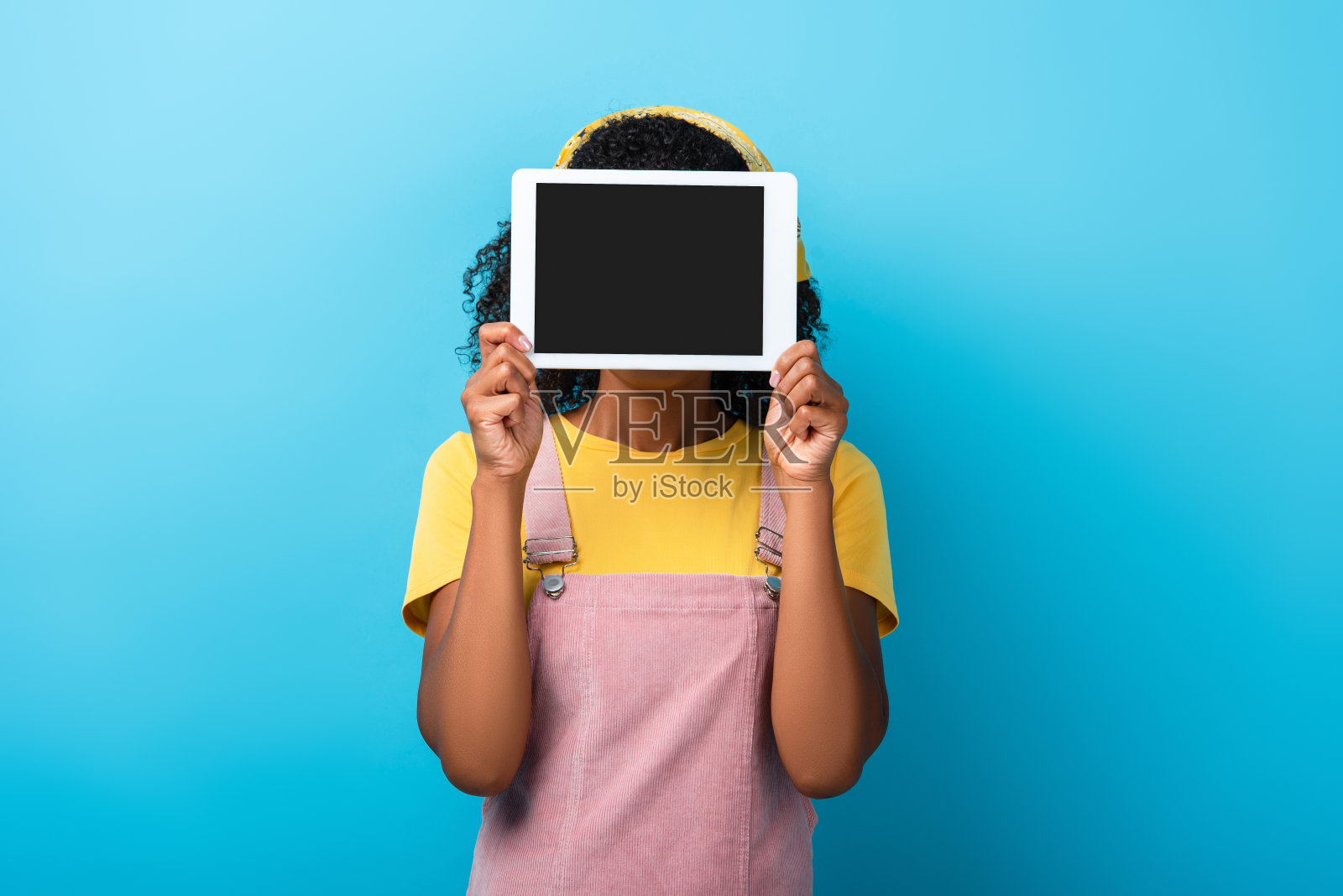 卷曲的非洲裔美国妇女遮住脸,手持蓝色空白屏幕的数字平板电脑照片摄影图片