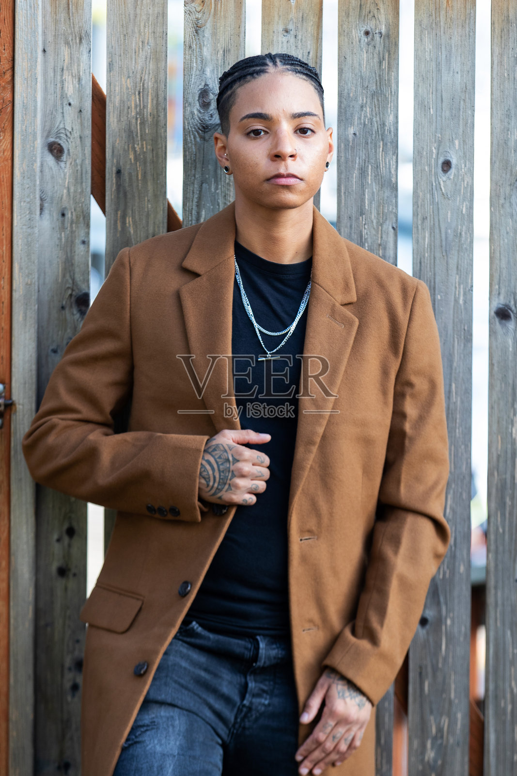 年轻的非洲裔美国妇女,梳着黑色的辫子,穿着一件棕色的长外套照片摄影图片