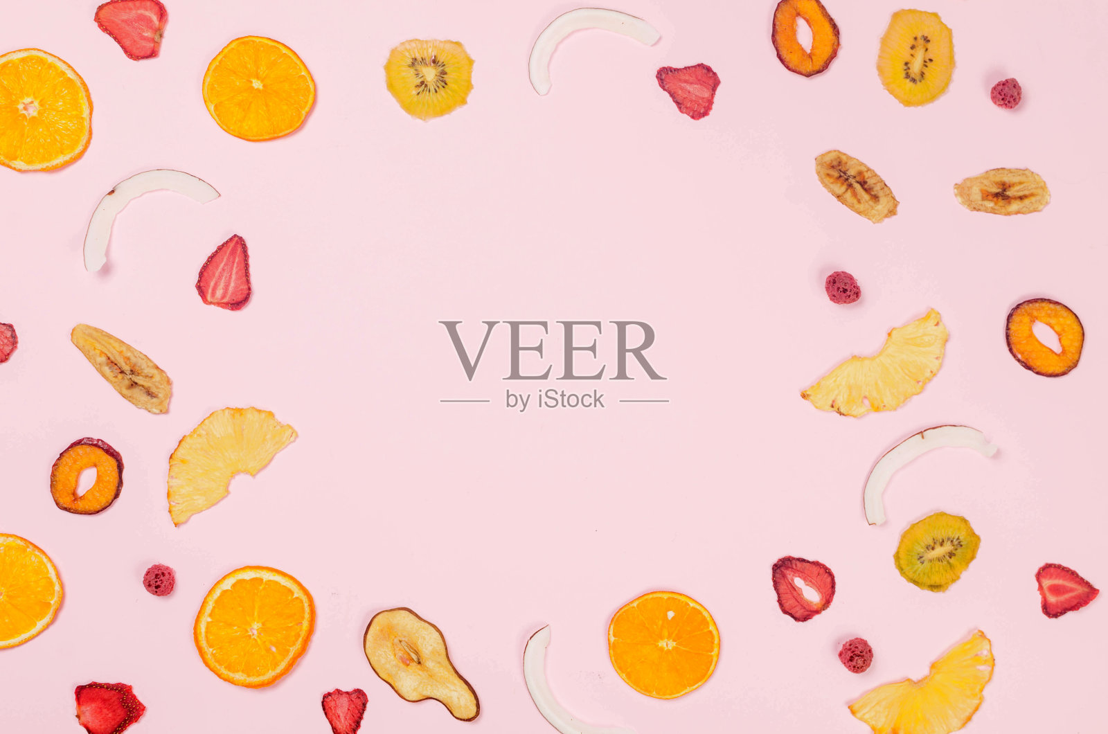 散布在粉红色背景上的什锦干果片。照片摄影图片