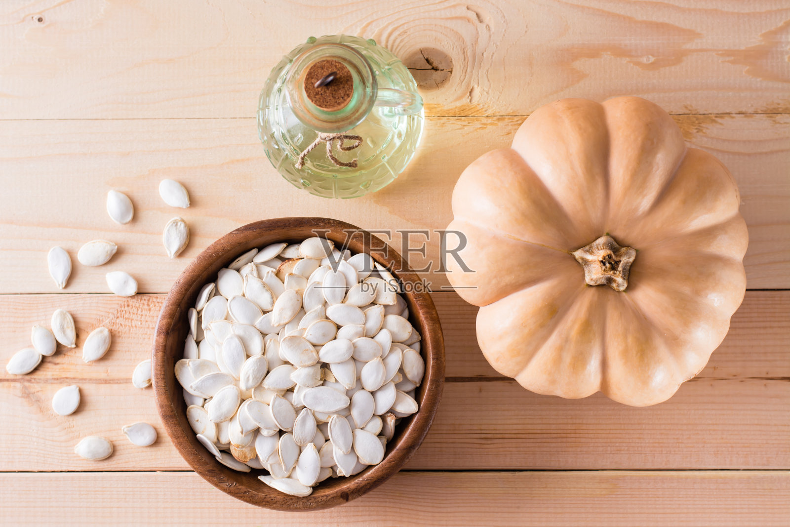 烤南瓜子在盘子里,油在瓶子里,南瓜在木桌上。俯视图照片摄影图片