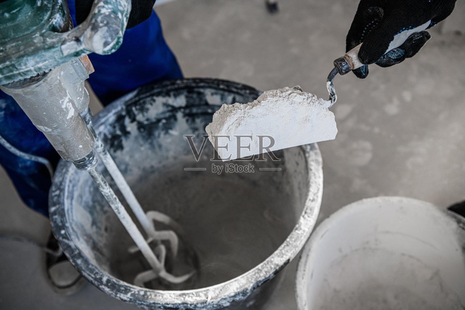 工匠用铲子把干水泥放入桶中照片摄影图片