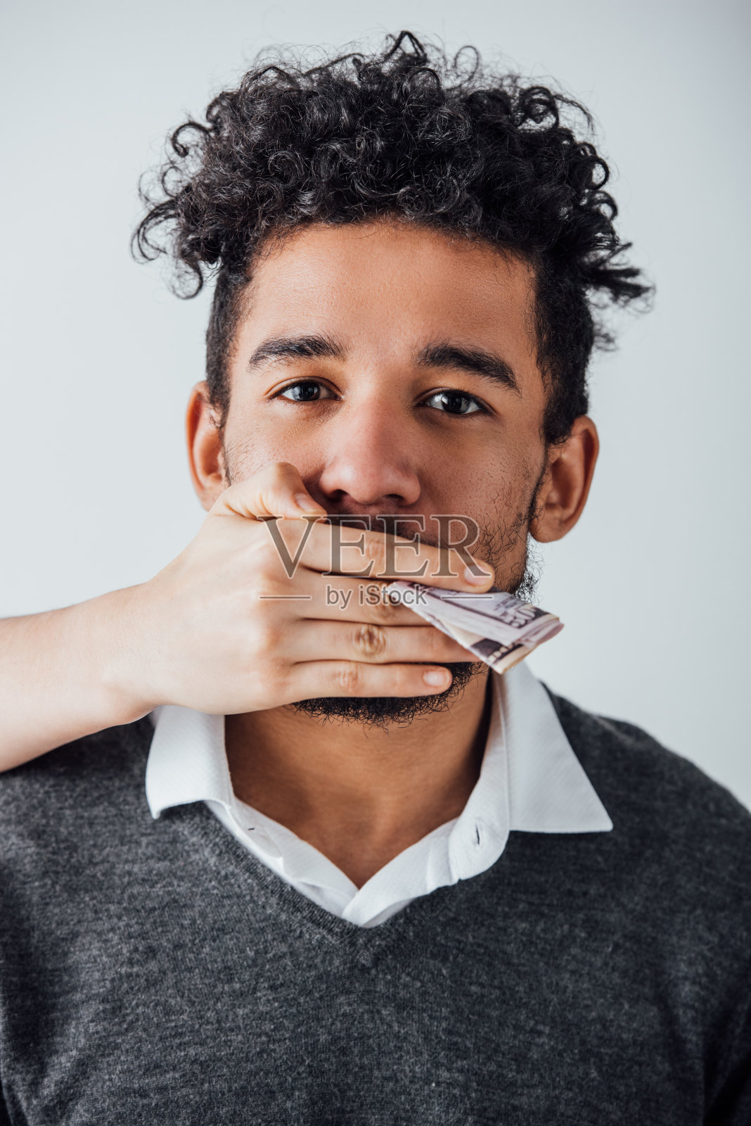 女性手里拿着美元钞票,一边捂着嘴,一边把非裔美国人孤立在灰色上照片摄影图片