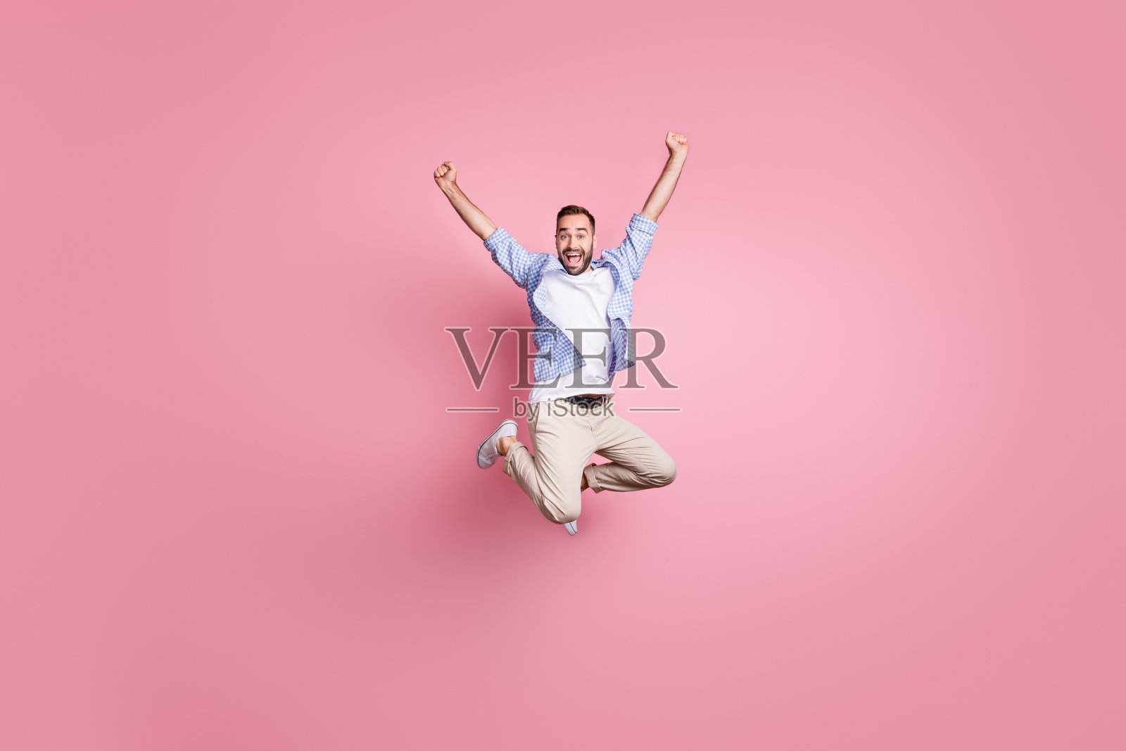 全长照片的家伙跳举起手臂庆祝胜利穿格子衬衫长裤运动鞋孤立的粉色背景照片摄影图片