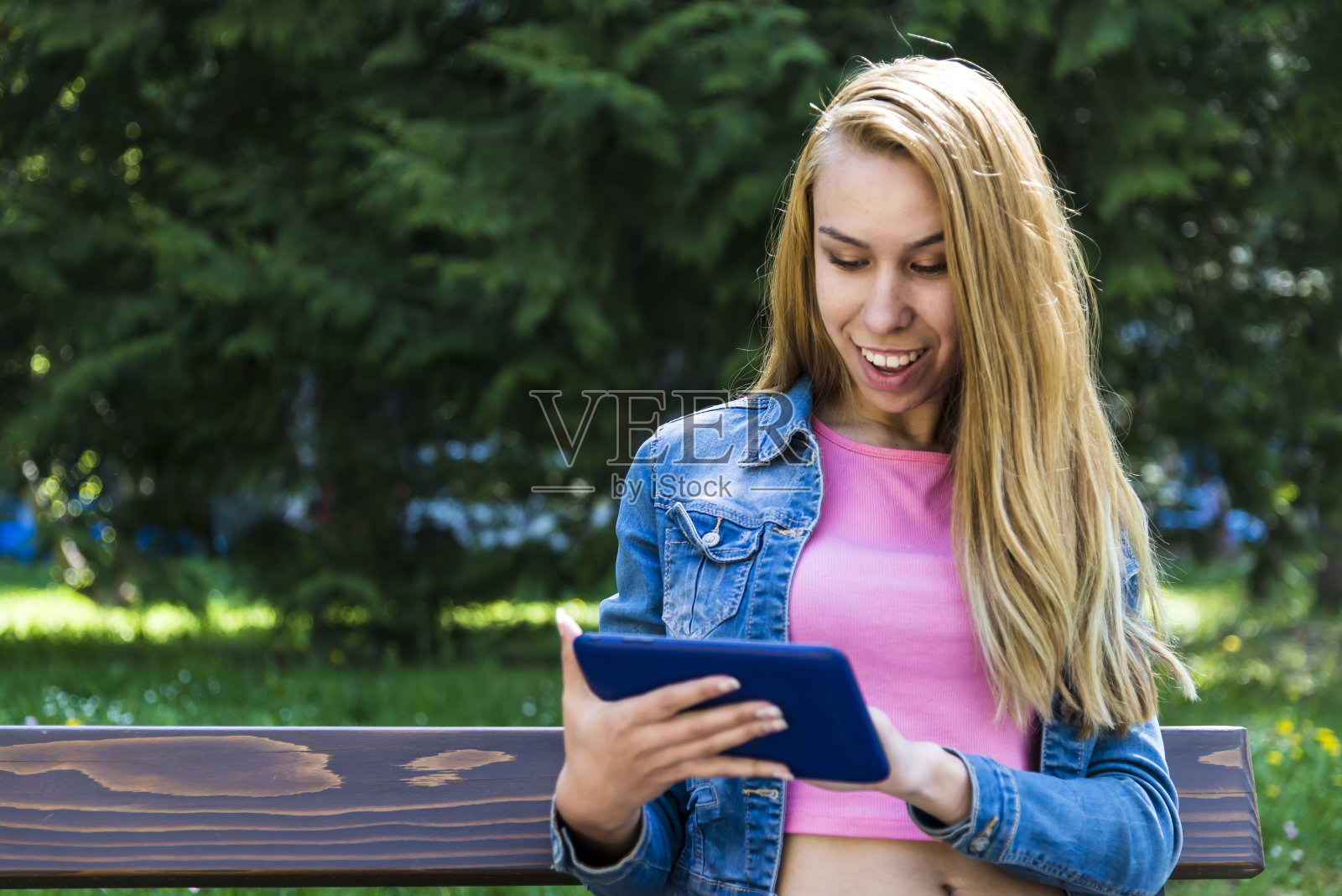 微笑的女人在公园里用平板电脑照片摄影图片