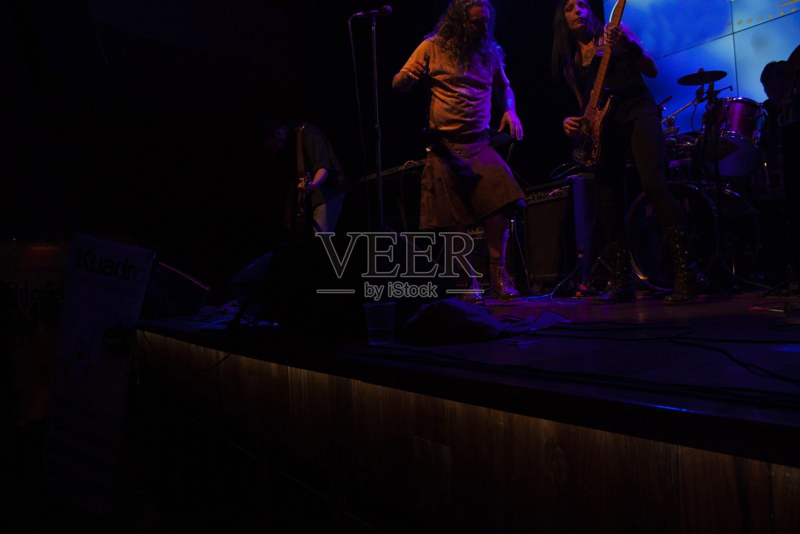 女人热情洋溢地弹奏贝斯,而歌手随着音乐的声音跳舞,在墨西哥城的夜生活照片摄影图片