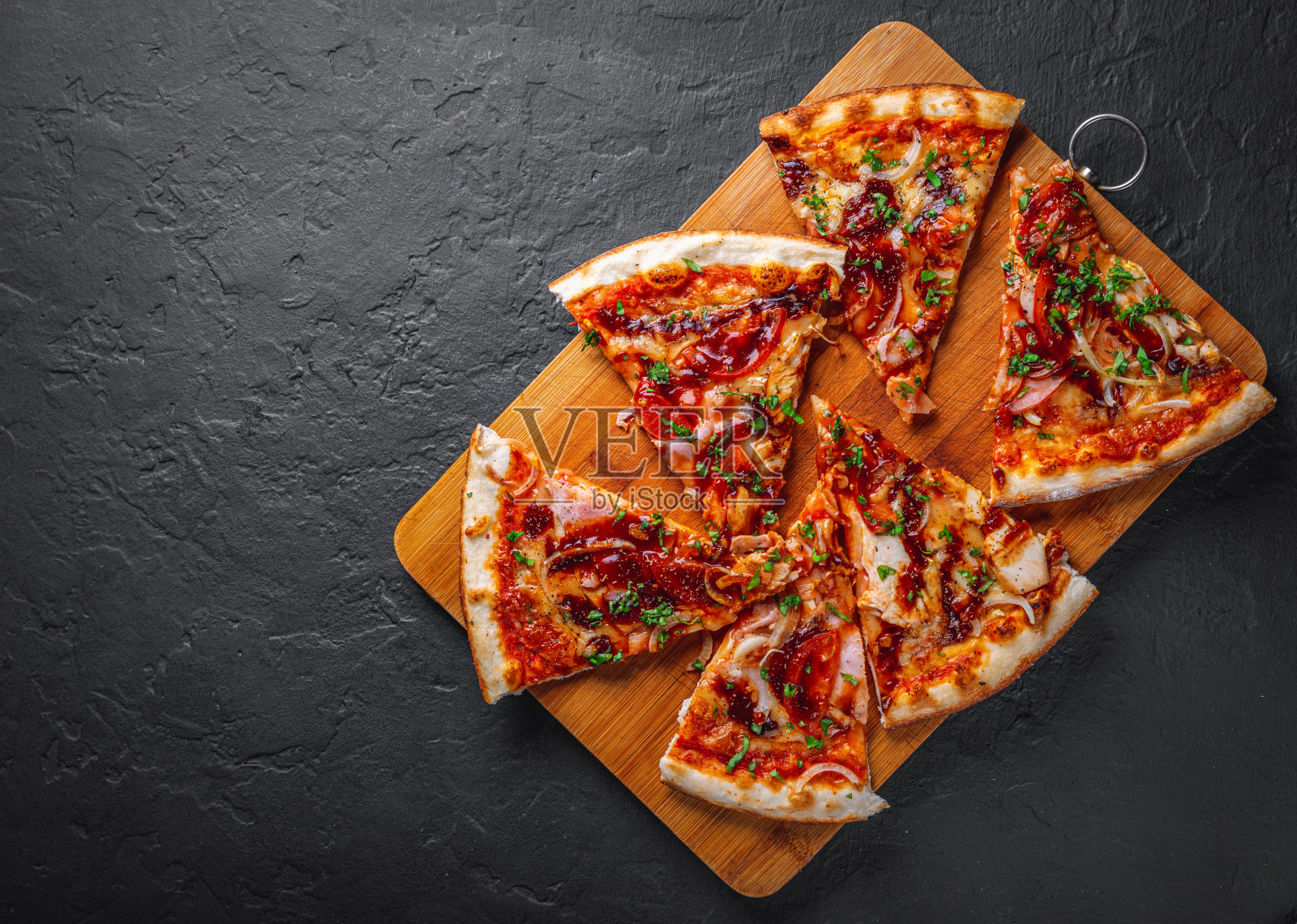 鸡肉和烧烤酱的披萨片。意大利披萨在深灰色的黑色石板背景照片摄影图片