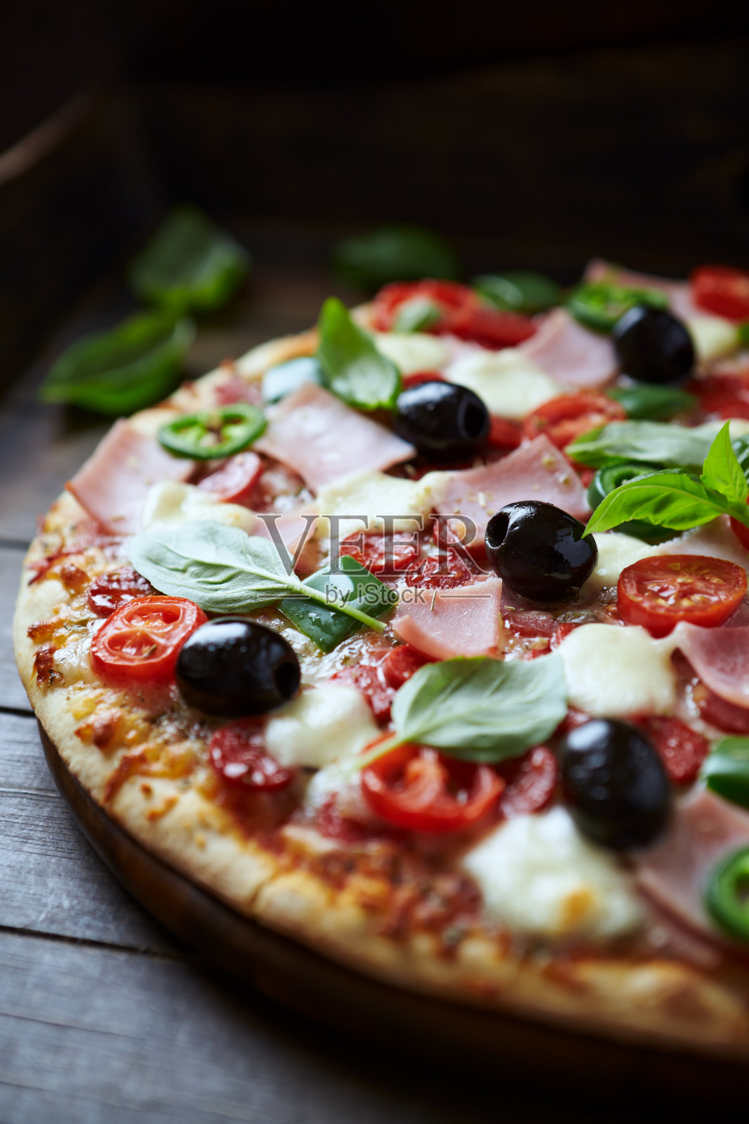 火腿、马苏里拉芝士、樱桃番茄、青椒、墨西哥胡椒、黑橄榄和新鲜罗勒。黑暗的背景。关闭了。照片摄影图片