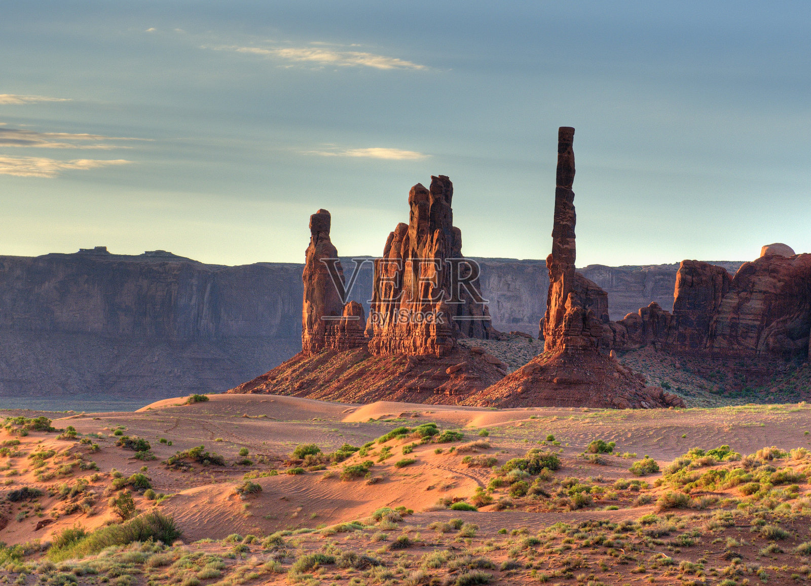 在亚利桑那纪念碑谷的沙丘上的图腾柱在一个晴朗的夏日早晨与晴朗的蓝色天空和几朵云照片摄影图片