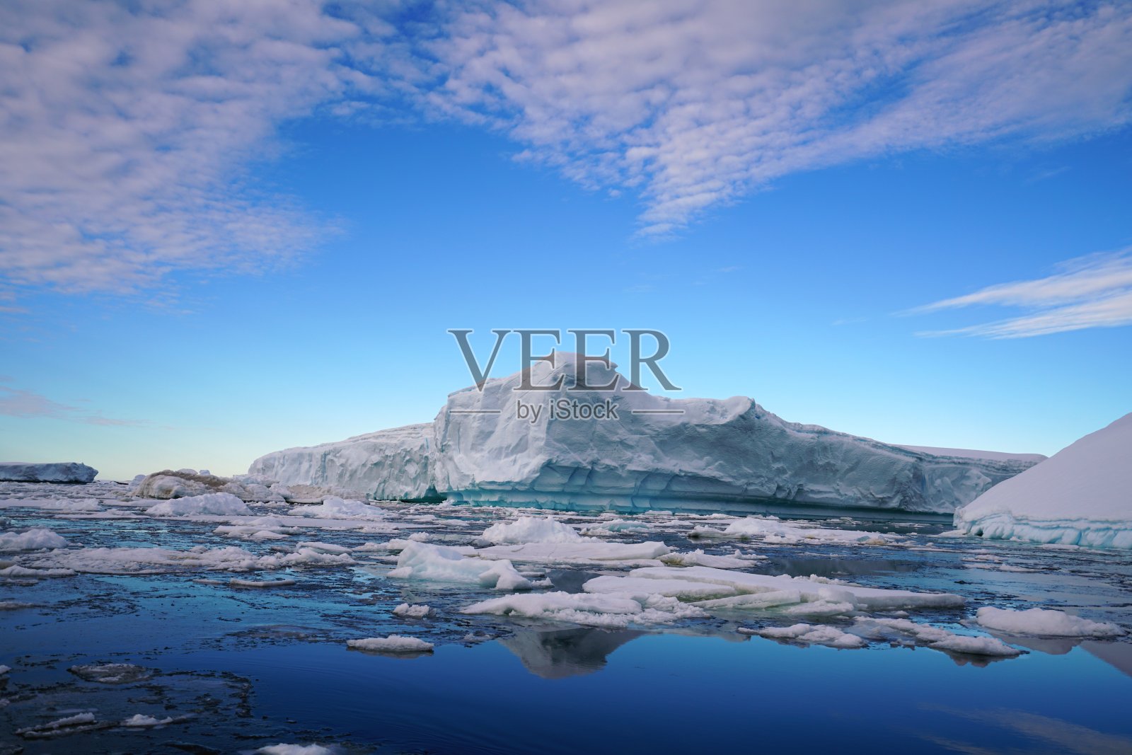 一些融化的碎冰漂浮在海上。蓝色的天空和辐射状的云是南极洲夏季的景观。照片摄影图片