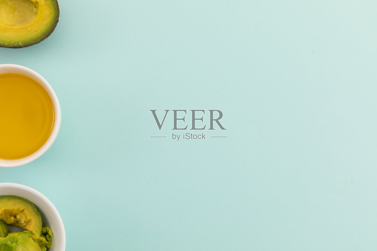 一碗切成两半的牛油果,在蓝色背景上调味照片摄影图片