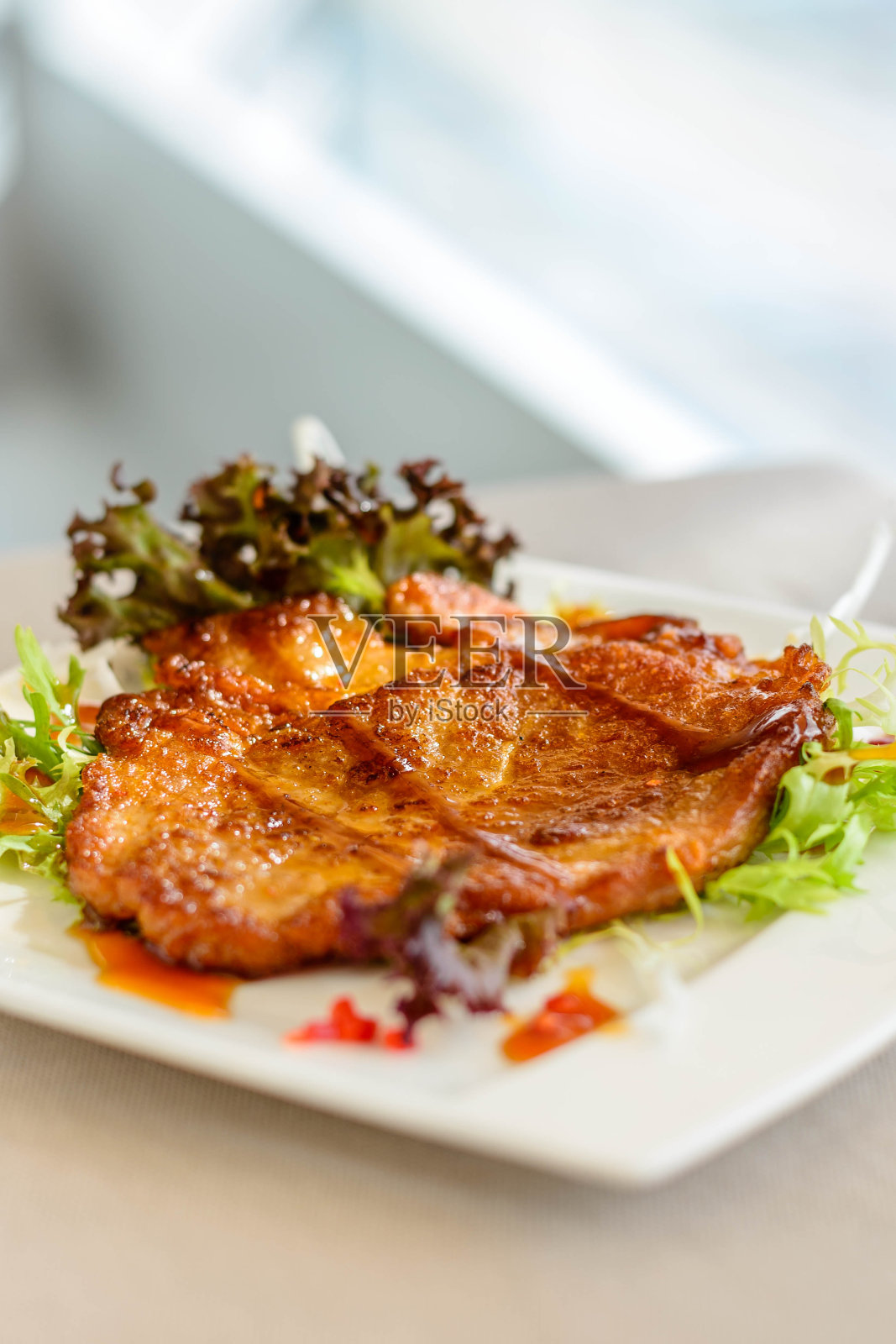 主菜是炒猪排配生菜,放在白色盘子里照片摄影图片