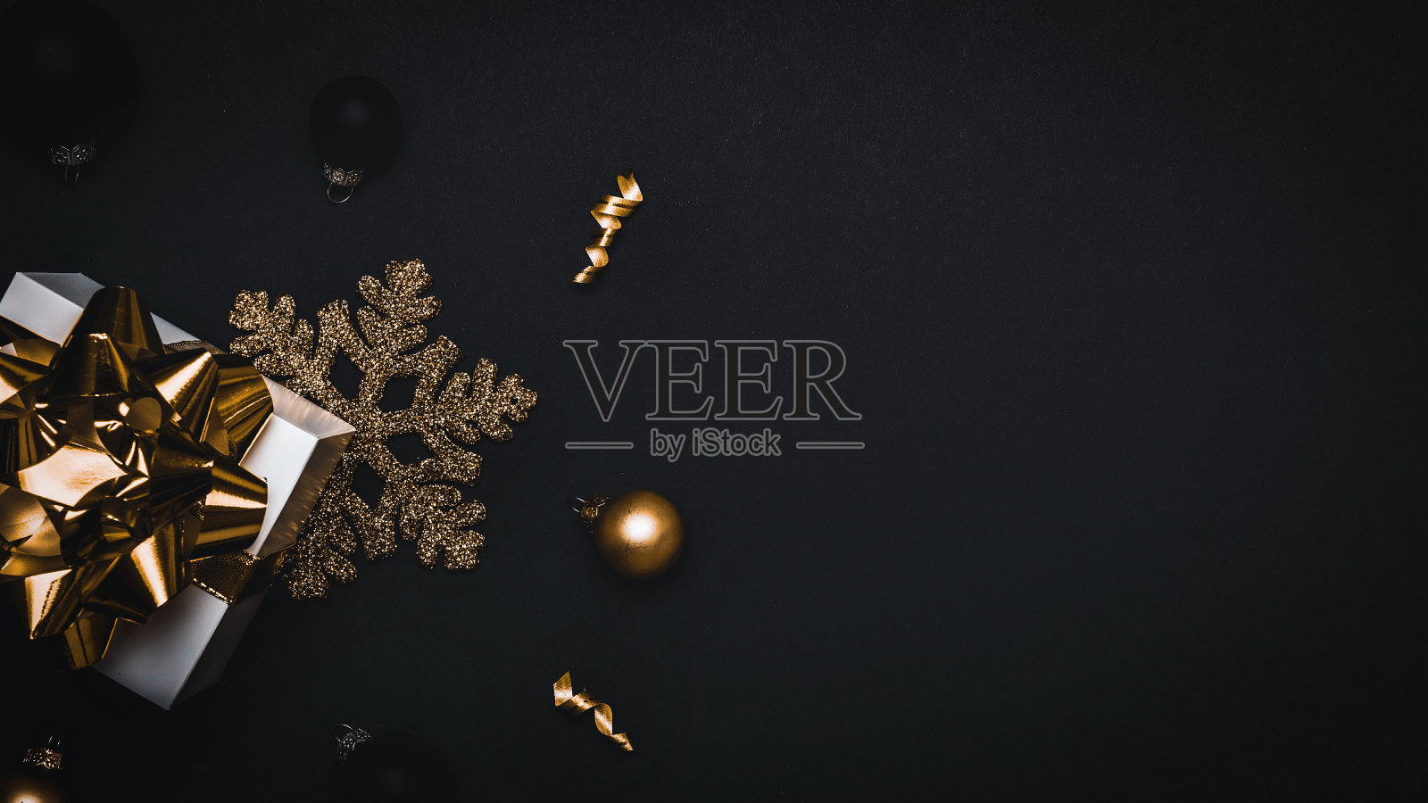 圣诞节销售。白色礼物与金色的弓,金色的球和闪闪发光的灯花环圣诞装饰在黑暗的背景贺卡。文本的装饰和复制空间。照片摄影图片