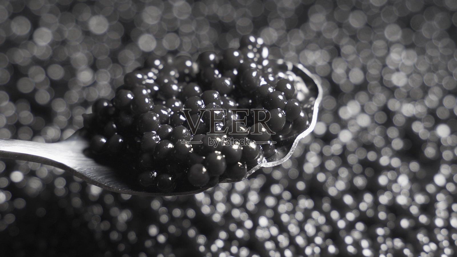 勺子里的黑鱼子酱在一个旋转的背景上照片摄影图片