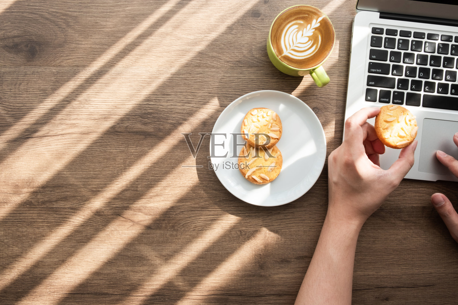 男人一边吃饼干一边用笔记本电脑。早上喝咖啡的工作理念。顶视图与复制空间,平放。照片摄影图片