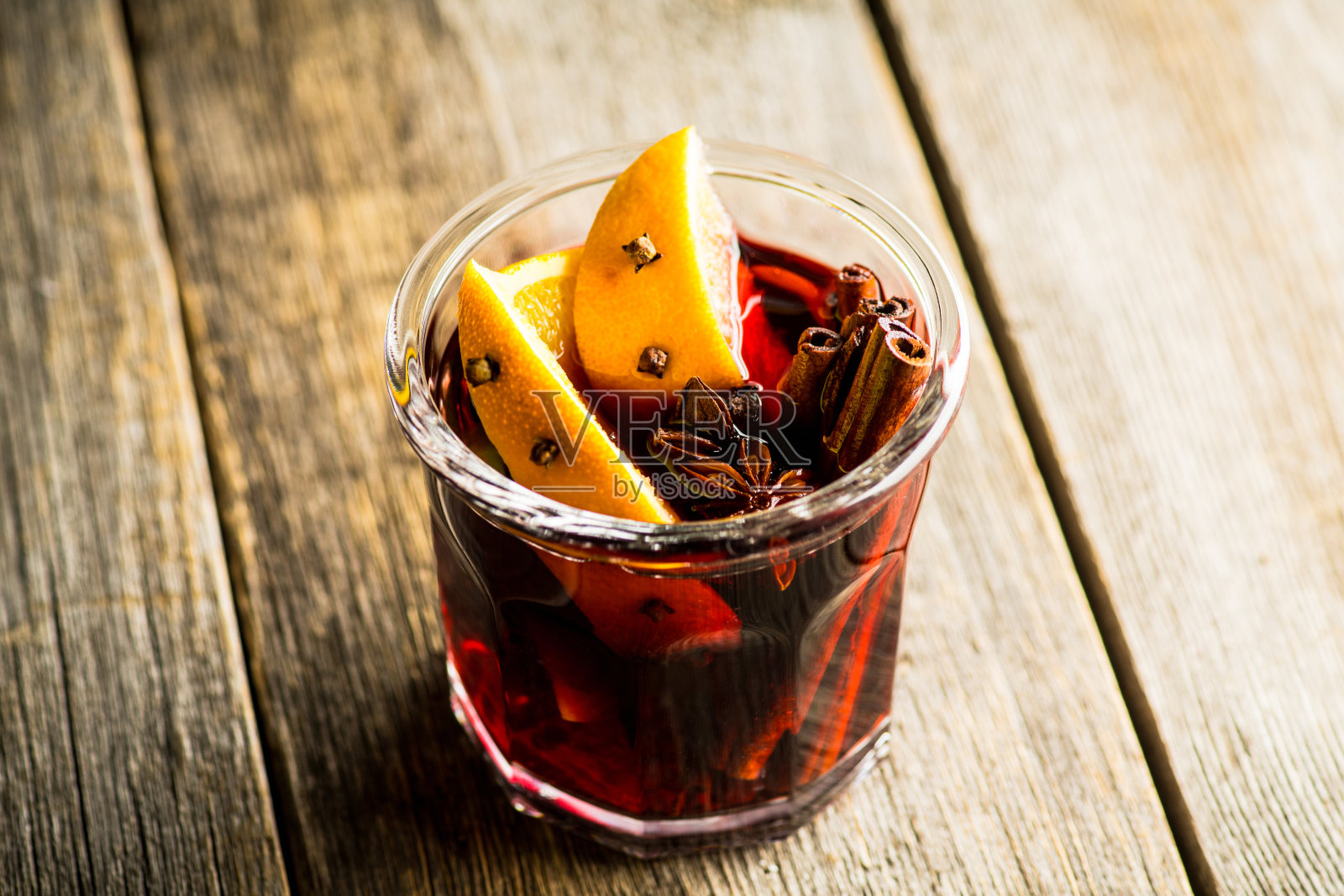 在乡村的背景下,用玻璃杯加热红酒与橙子和不同的香料。圣诞节的食物。冬天的装饰品。照片摄影图片