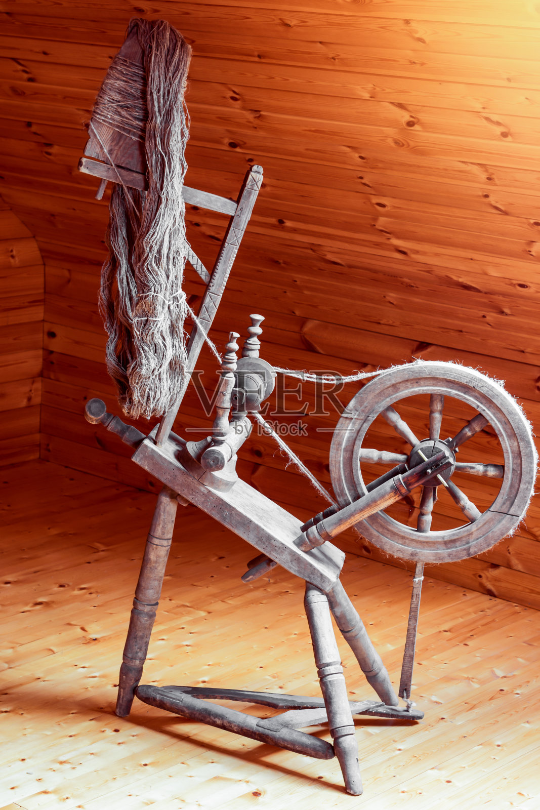 在有木墙的房间里用橡木制成的古代木制纺车照片摄影图片