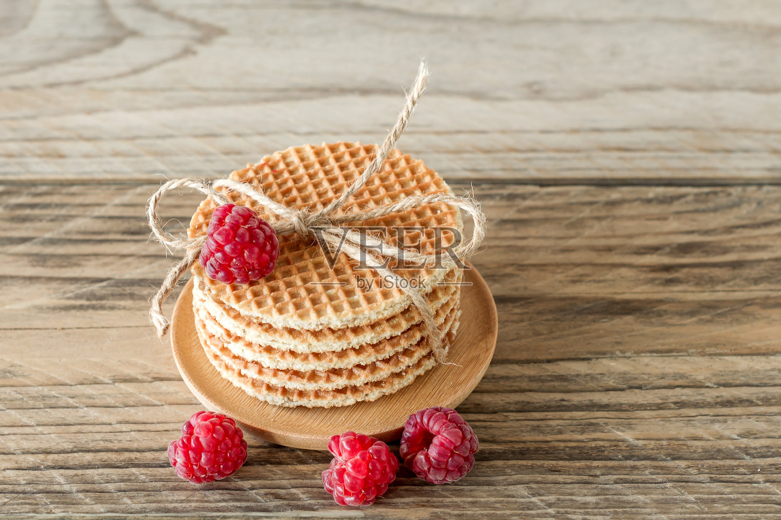 木桌上有一堆焦糖荷兰圆饼和覆盆子照片摄影图片