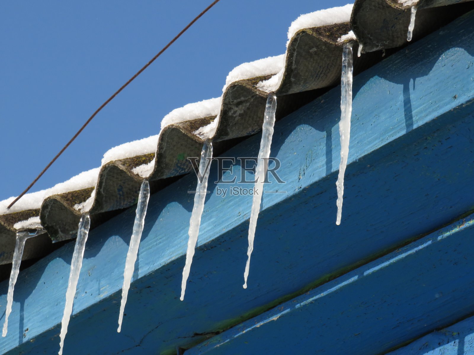 11月的一个阳光明媚的日子,木屋屋顶上的冰柱照片摄影图片