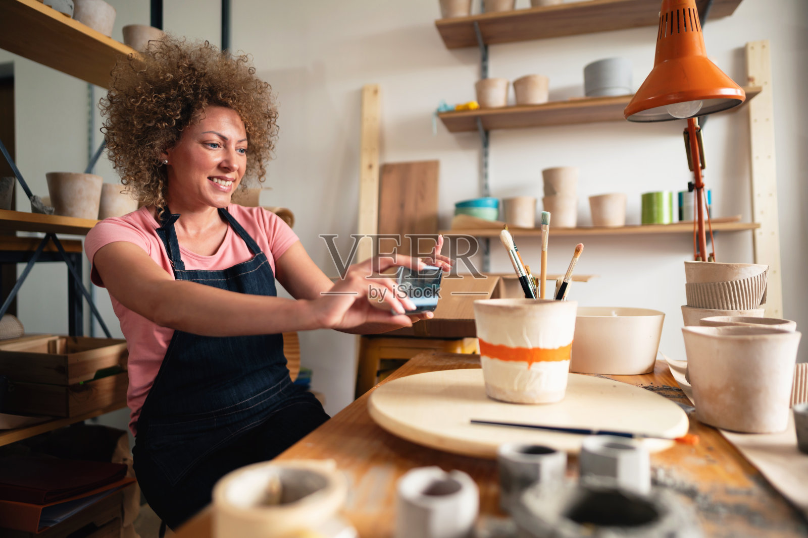 微笑的小企业主在工作室拍摄花盆照片摄影图片
