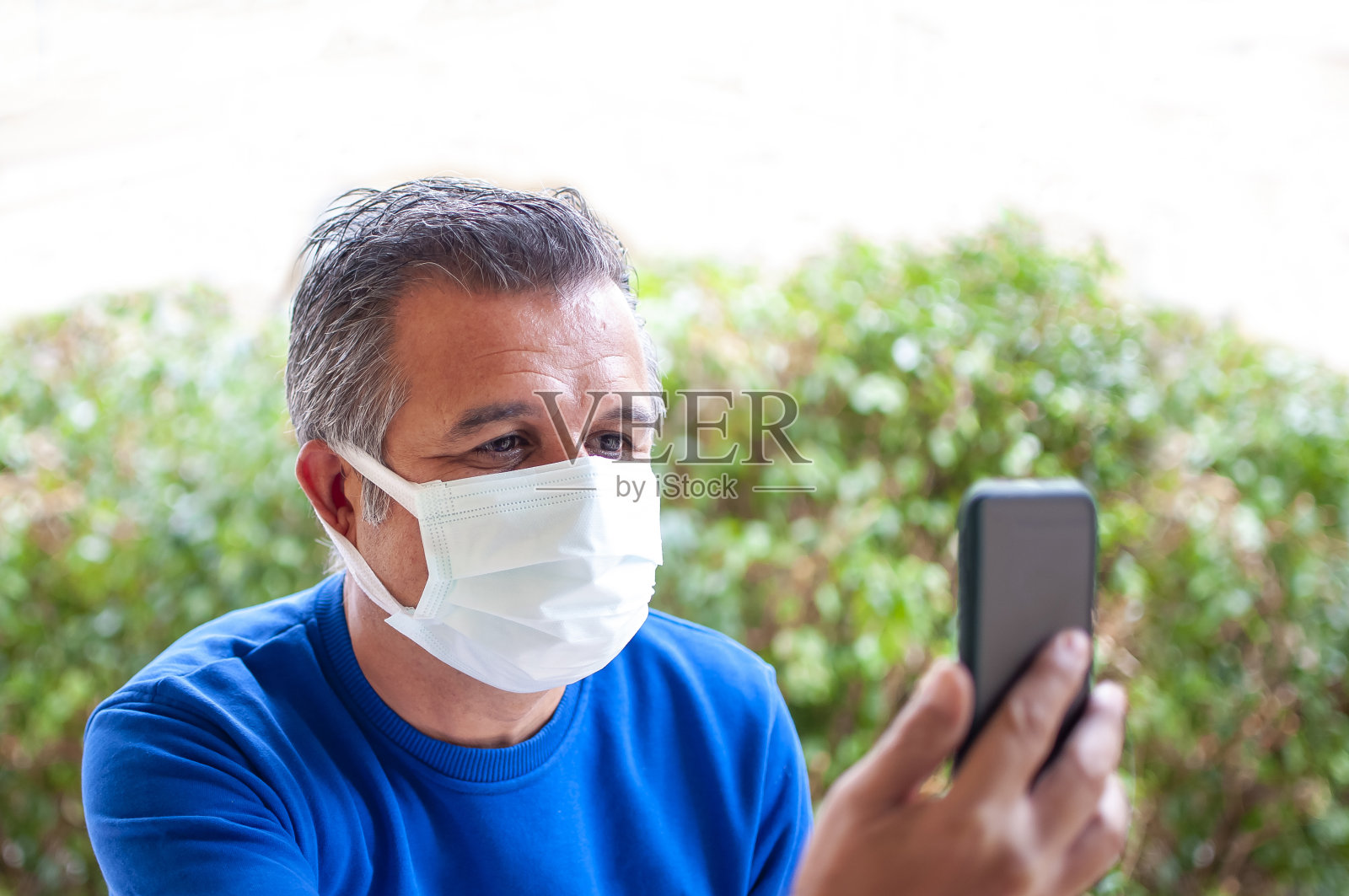 英俊的使用手机在户外与口罩照片摄影图片