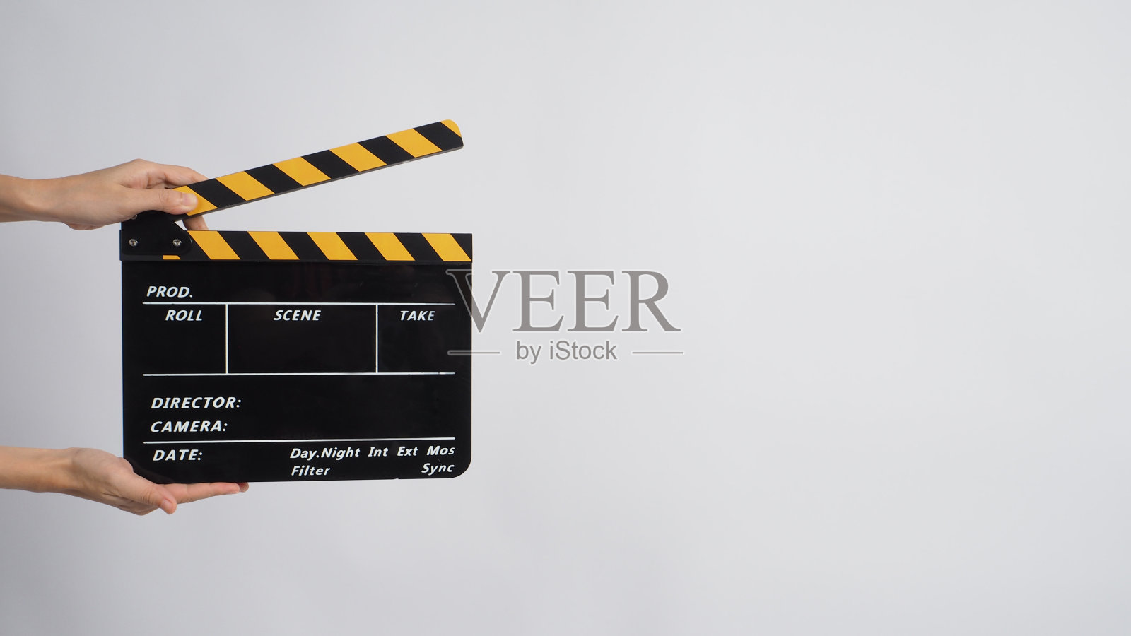 两只手拿着黑色和黄色拍板在白色背景上。照片摄影图片