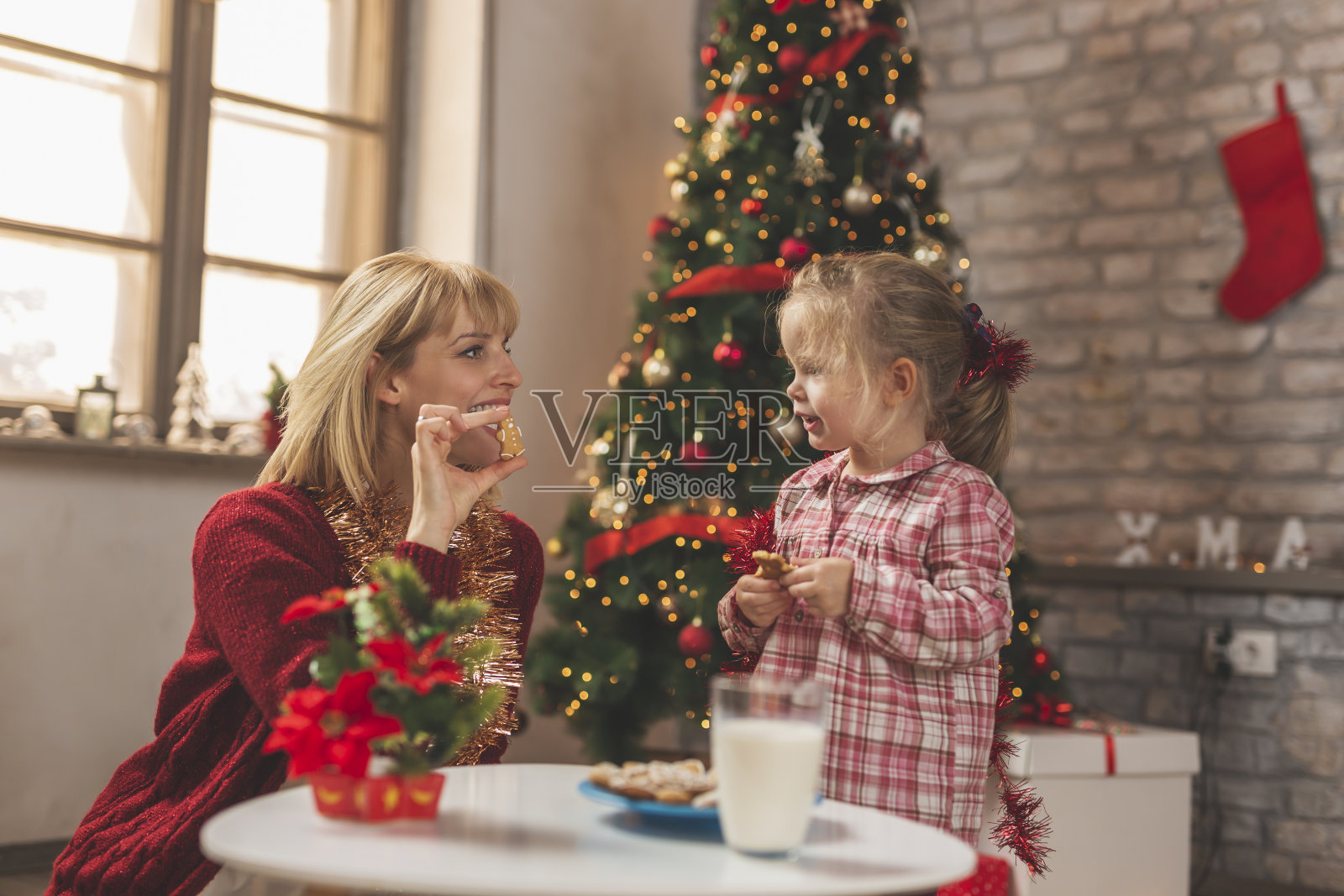 母女喝着牛奶,吃着圣诞姜饼照片摄影图片