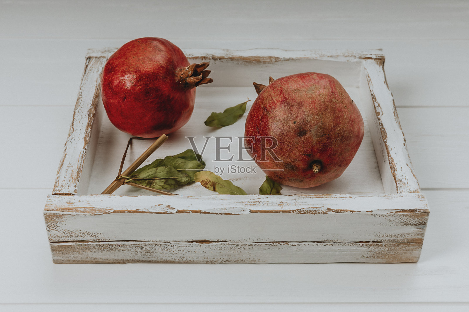 两个红石榴放在一个白色的木盒子里照片摄影图片