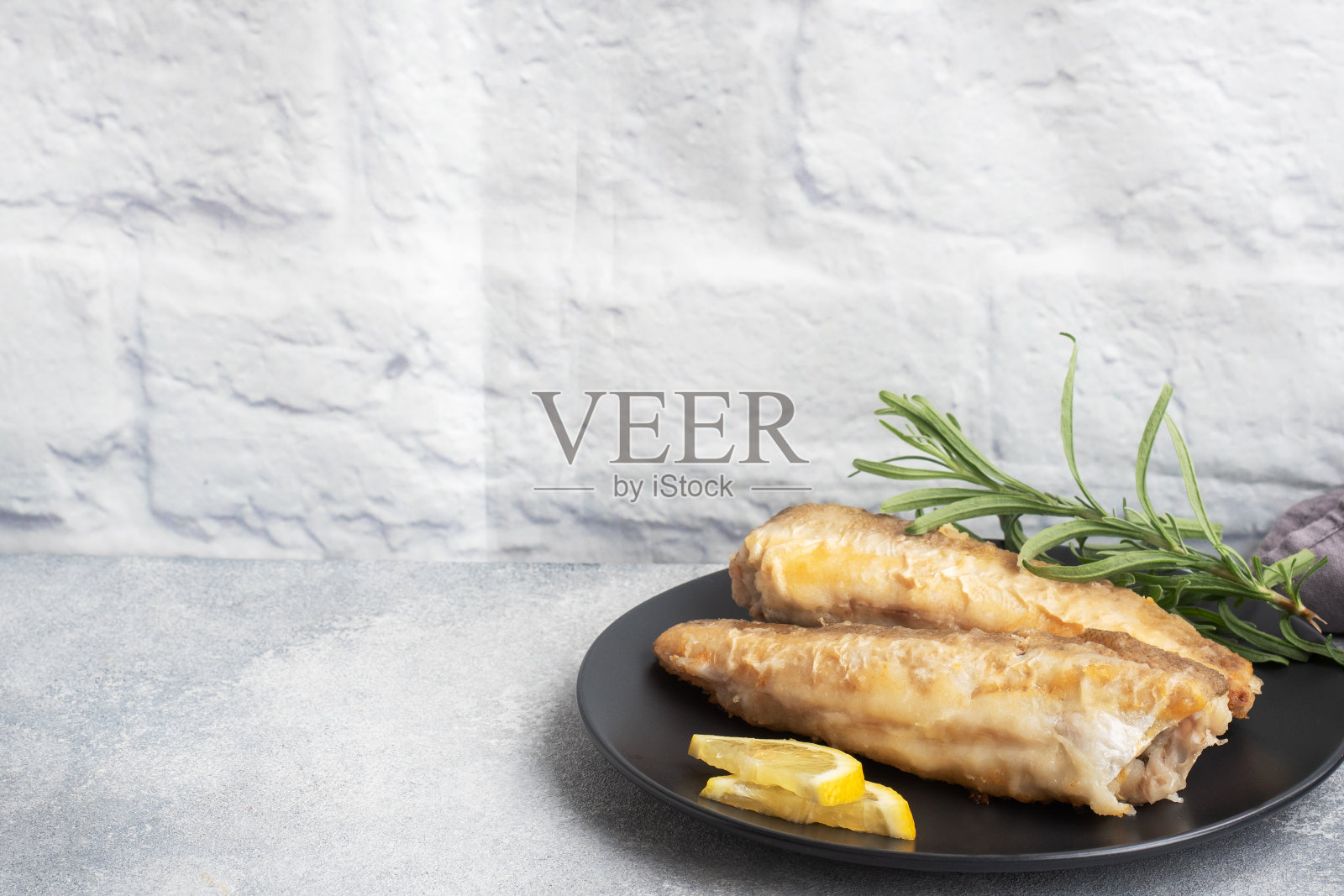 炸鱼,鳕鱼和新鲜柠檬片。灰色混凝土背景。副本的空间。照片摄影图片