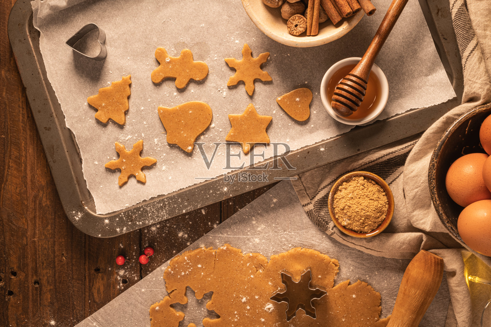 做圣诞姜饼。生面团做成姜饼人、圣诞树、星星、雪花等形状,放在纸盘上,用擀面杖放在质朴的桌子上。准备烤照片摄影图片