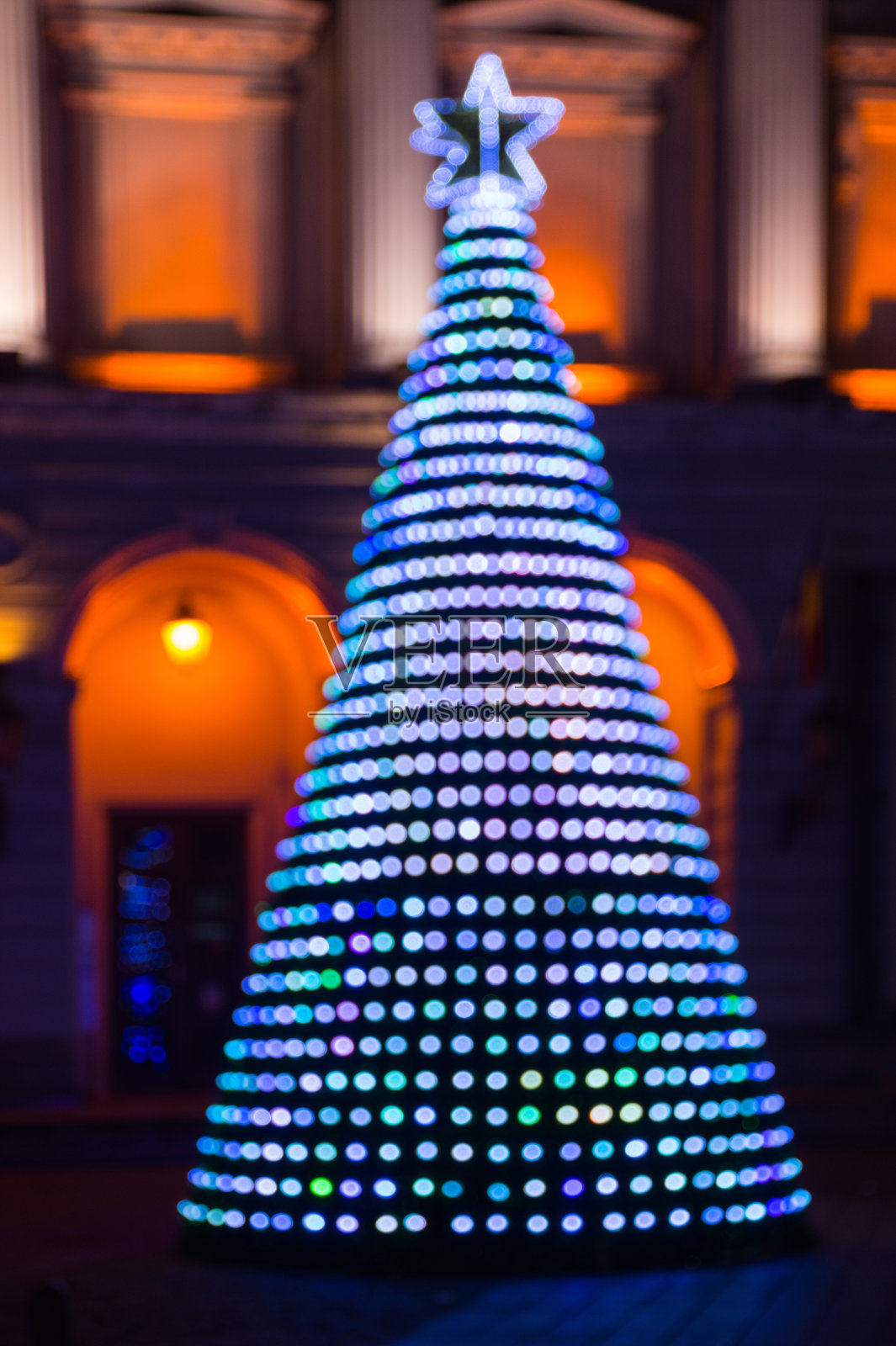 模糊的背景与彩色的圣诞树照亮了夜晚。照片摄影图片
