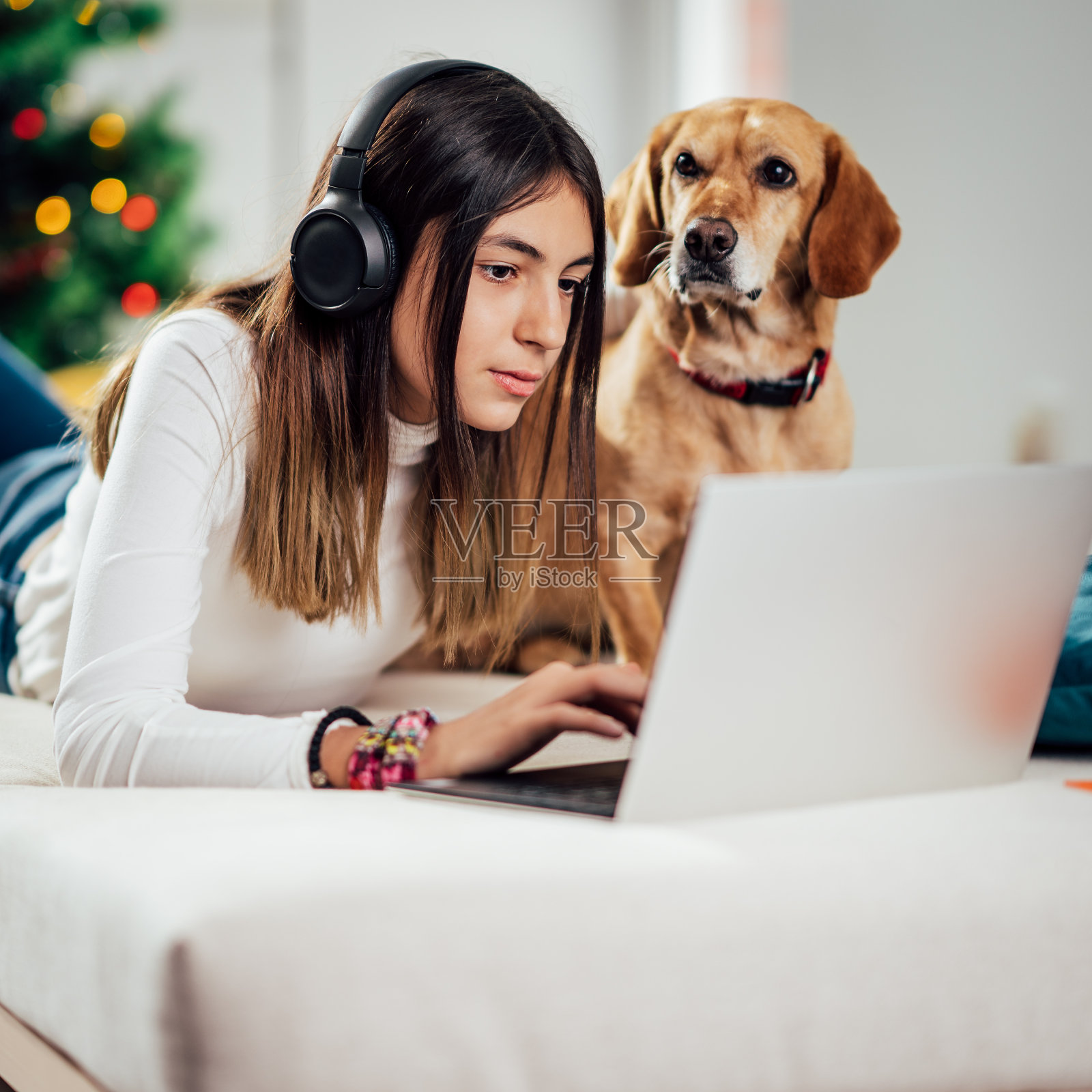 一个十几岁的女孩和她的狗躺在床上听音乐照片摄影图片
