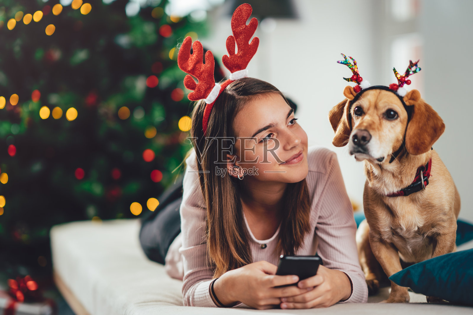 快乐的少女和她戴着鹿角的狗照片摄影图片