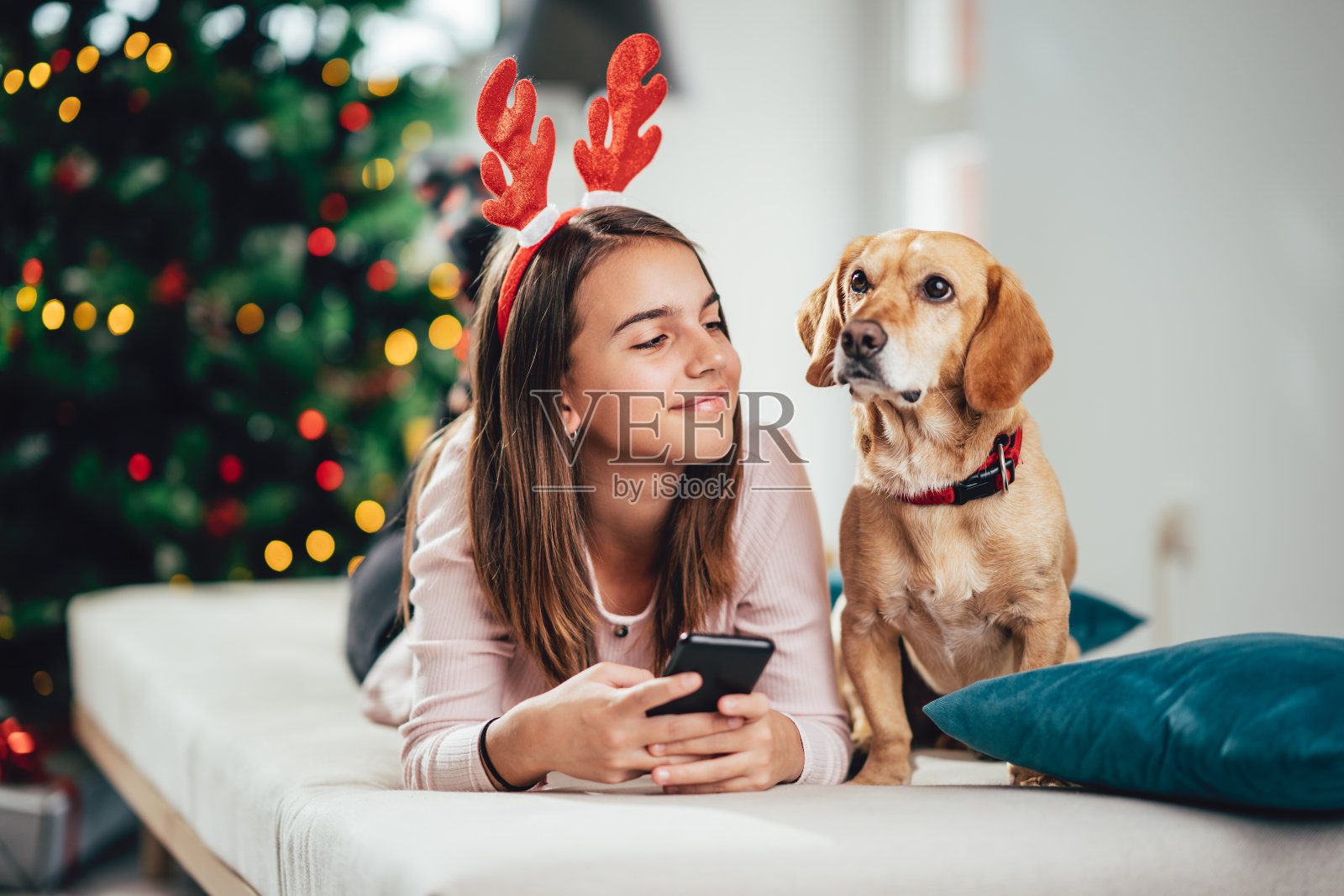 一个快乐的少女和她的狗一起享受圣诞节的早晨。照片摄影图片