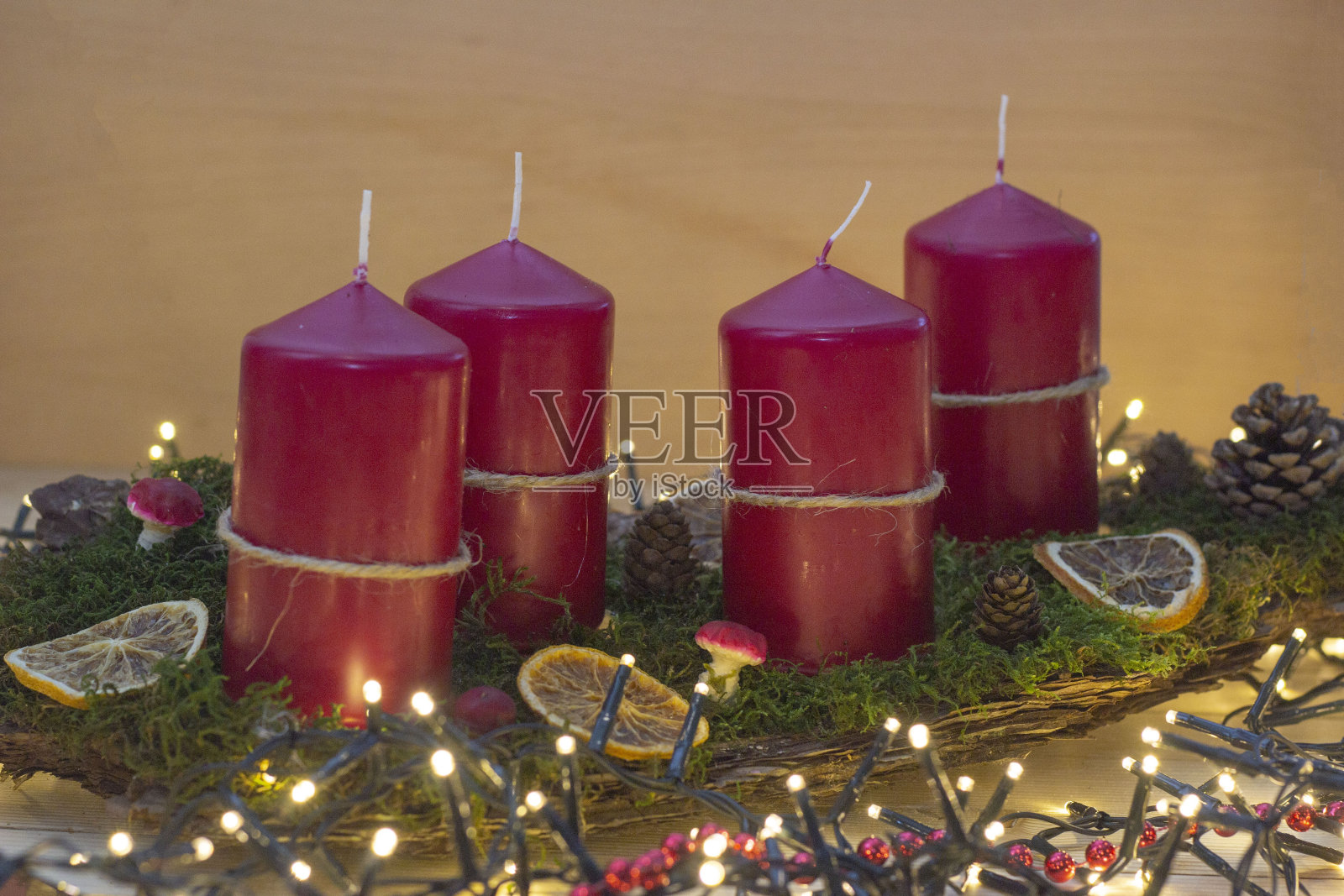 用红蜡烛、干橙、绿苔、树皮做成的花环放在摆满圣诞彩灯的桌子上照片摄影图片