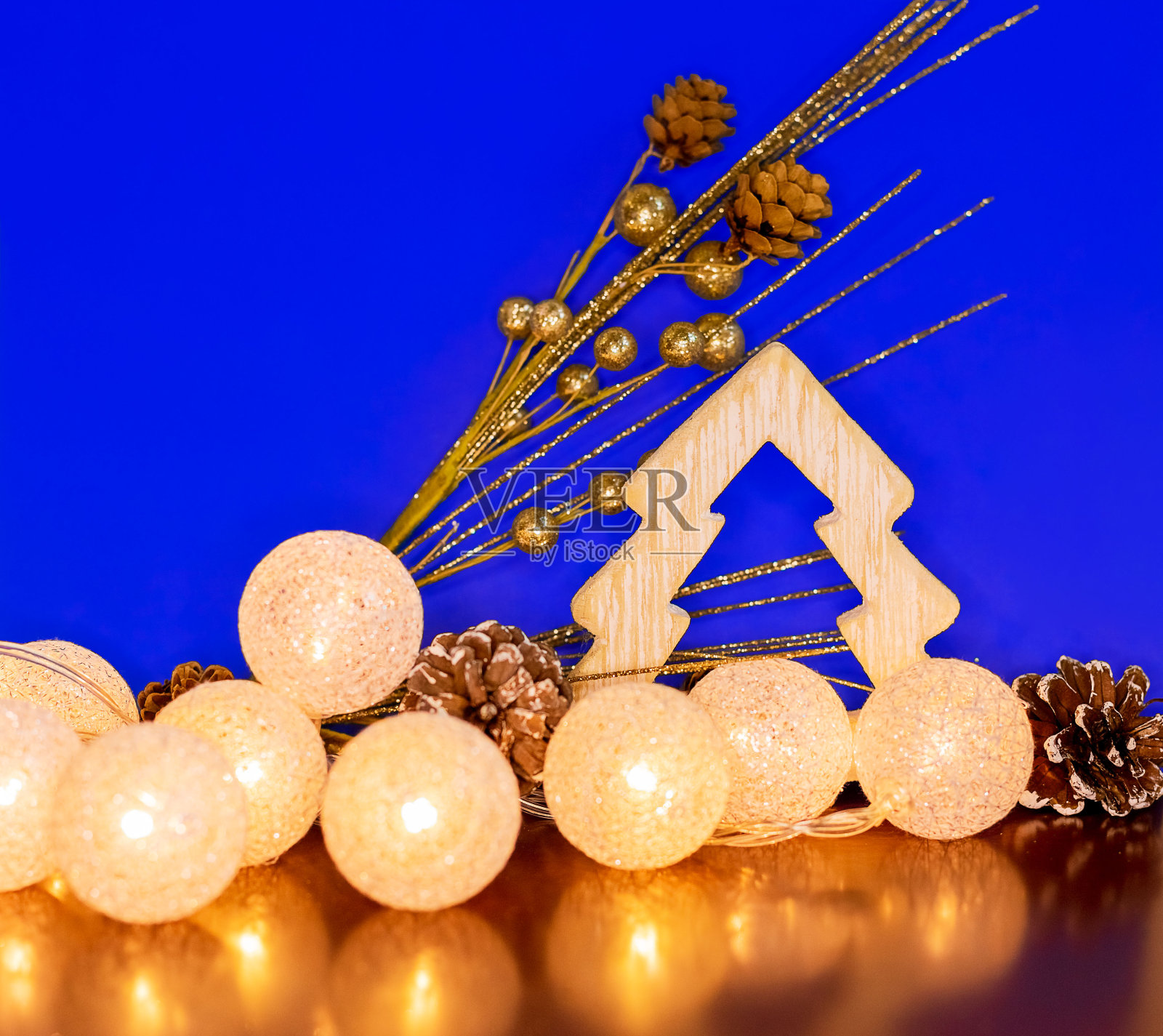 圣诞组成。圣诞花环,木制圣诞树和金色的树枝与锥体在蓝色的背景。新2021年。副本的空间。照片摄影图片