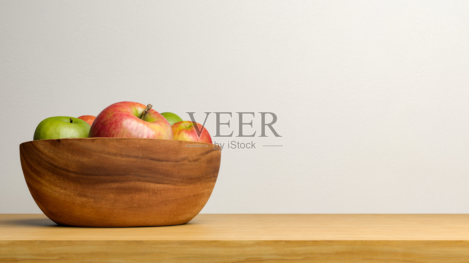 一个碗里装着红绿苹果,木桌上放着空白的复印空间。照片摄影图片