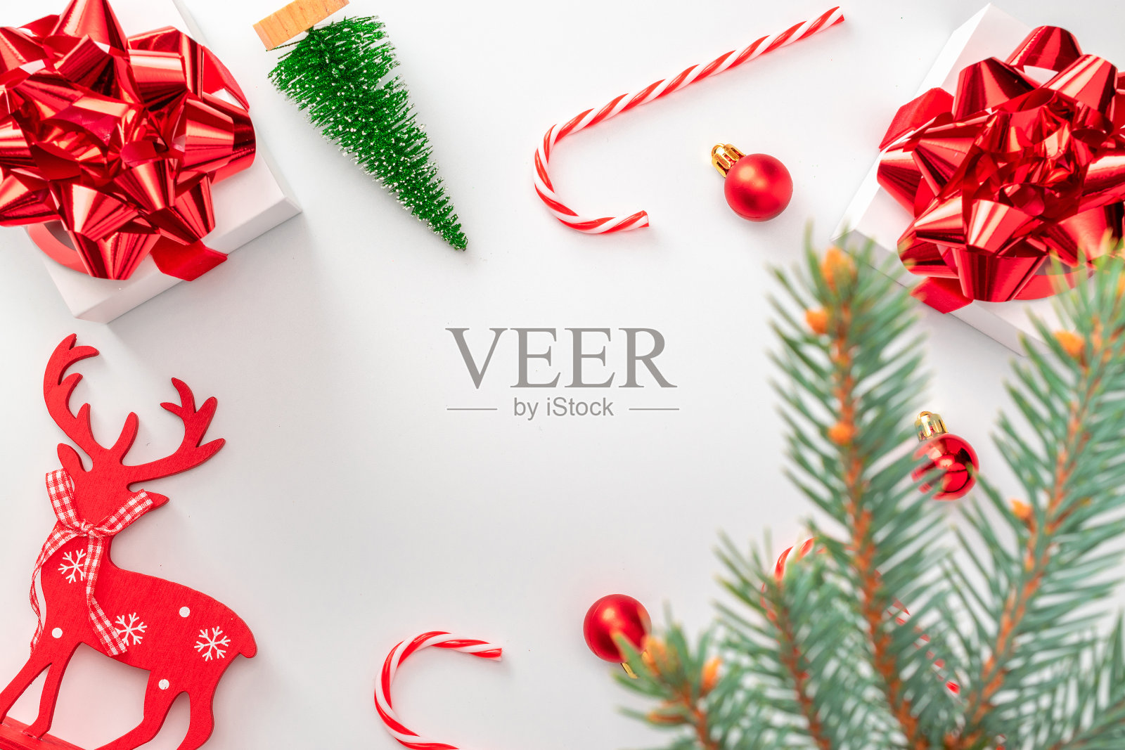 红色圣诞背景。白色礼盒与猩红丝带,新年球,糖果和闪闪发光的灯在圣诞节的组成在白色背景贺卡。平铺,俯视图,拷贝空间。照片摄影图片