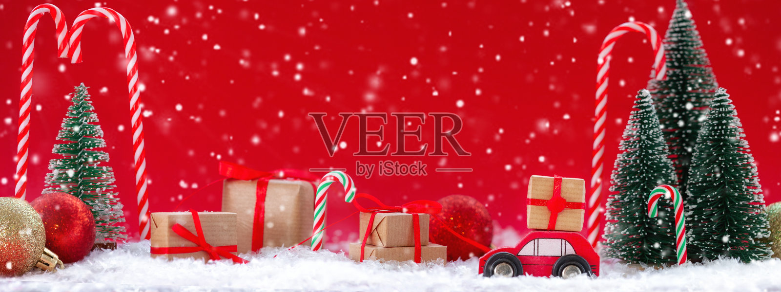 节日构图圣诞红车与礼盒在松林里许多不同的礼物在红色的背景。新年贺卡的概念照片摄影图片