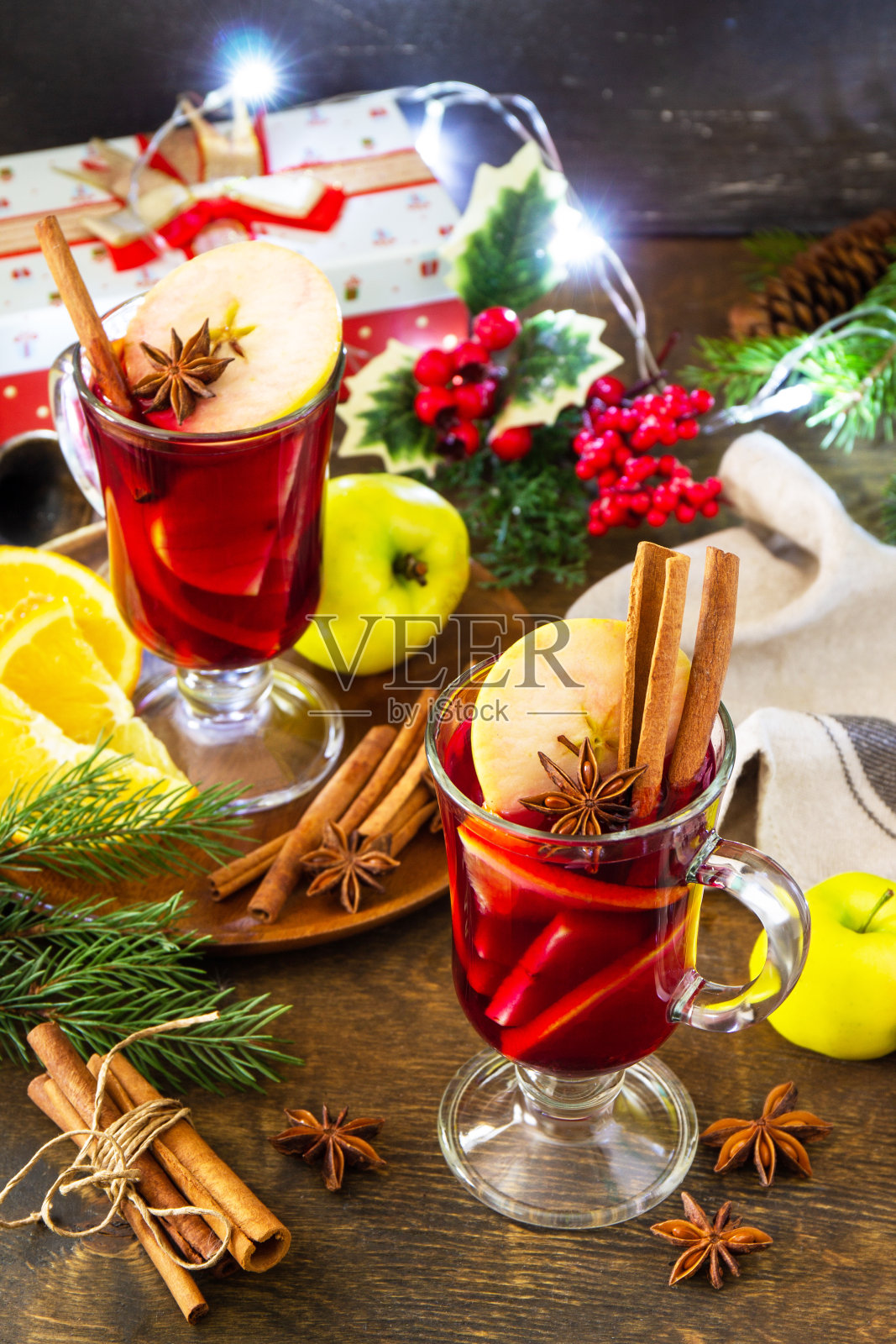 热葡萄酒在玻璃杯和香料在乡村的桌子上。冬季圣诞热饮,橙,苹果和香料。照片摄影图片