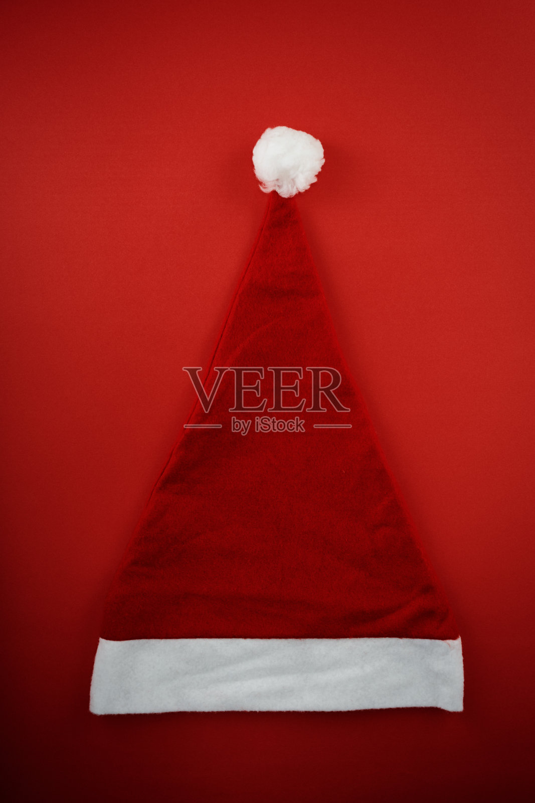圣诞老人的帽子在红色的背景平放直接从上面看照片摄影图片