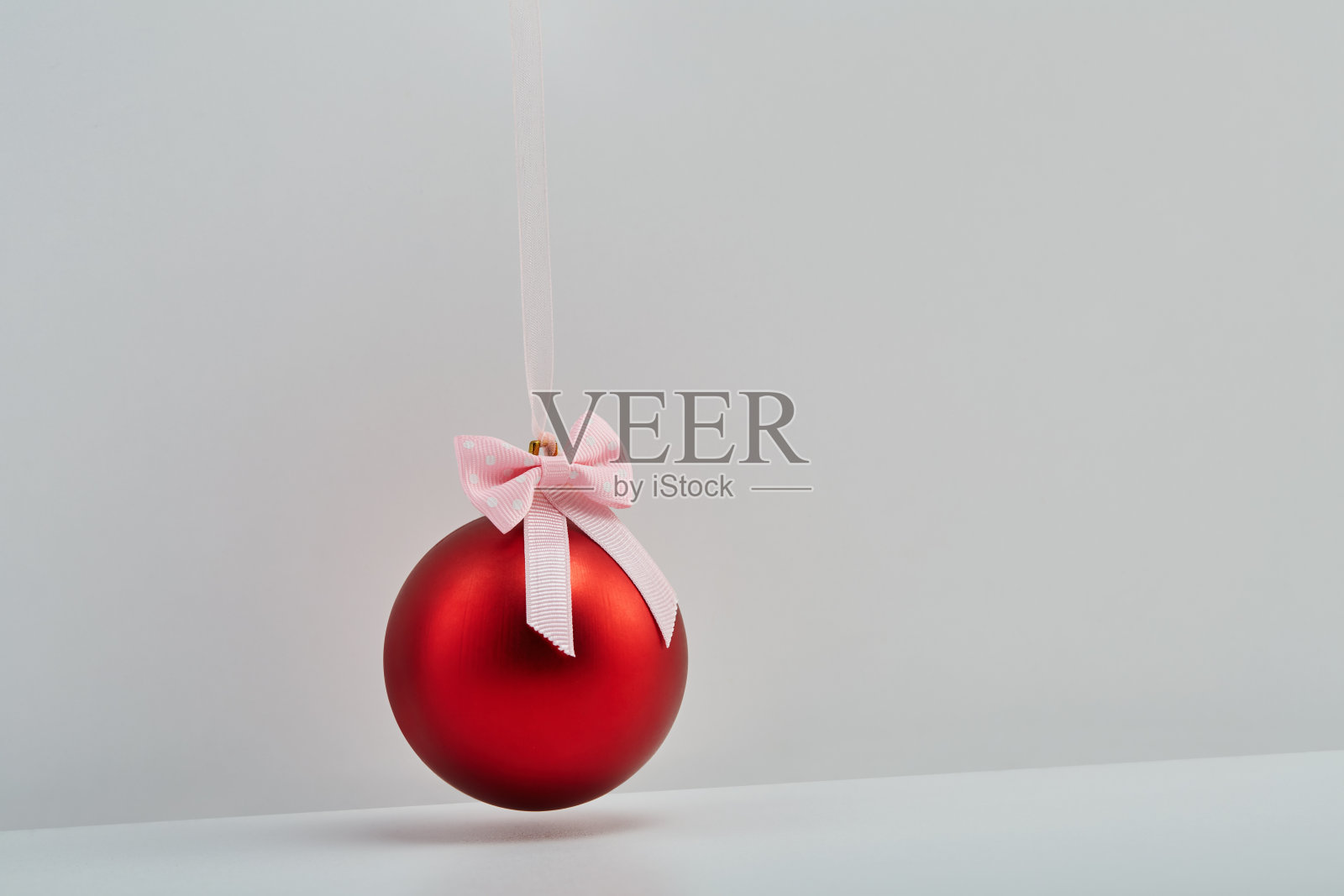 红色圣诞球挂在丝带和一个蝴蝶结在白色的背景照片摄影图片