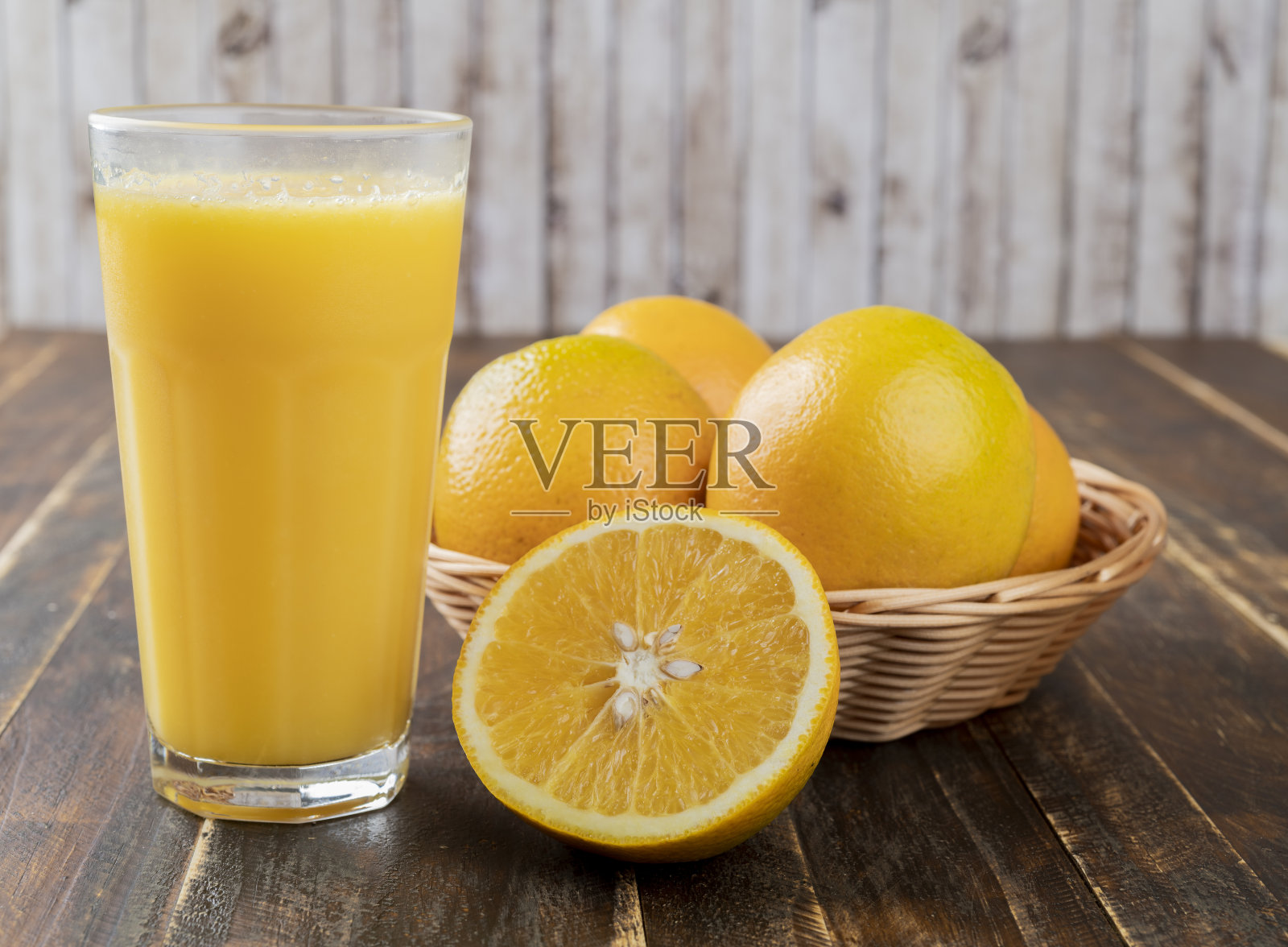 橙汁和装在篮子里的橙子,切好的水果放在木桌上照片摄影图片