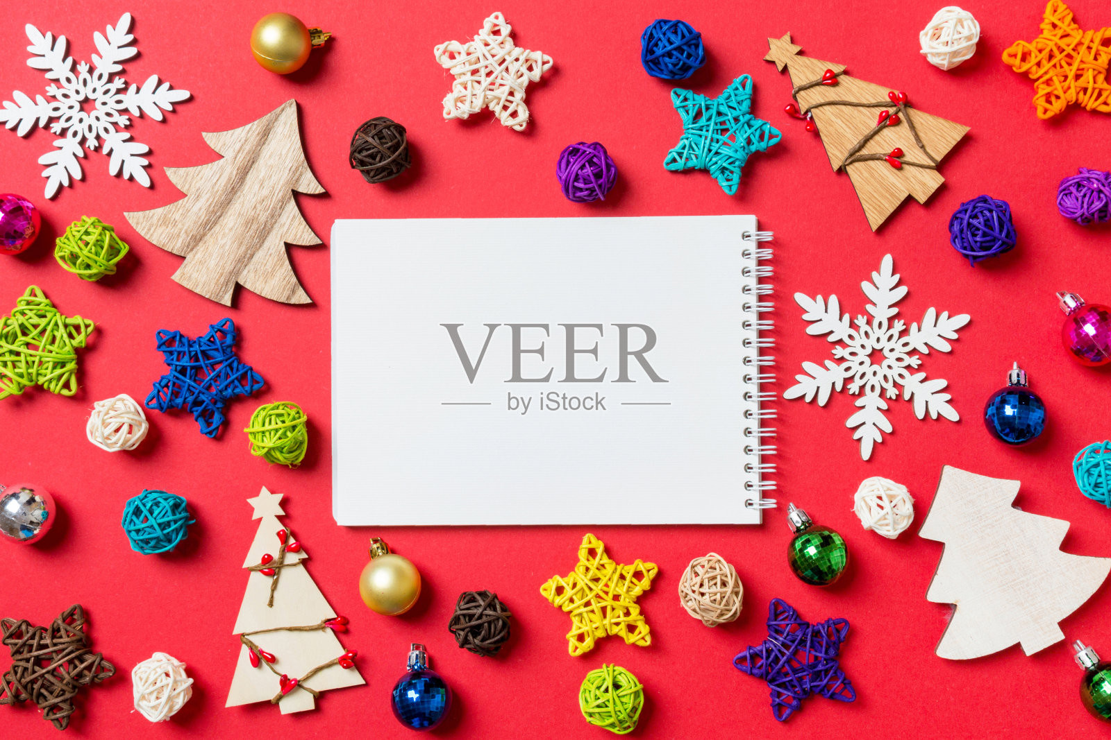 红色背景上的笔记本俯视图,由节日装饰品和玩具制成,圣诞装饰概念照片摄影图片