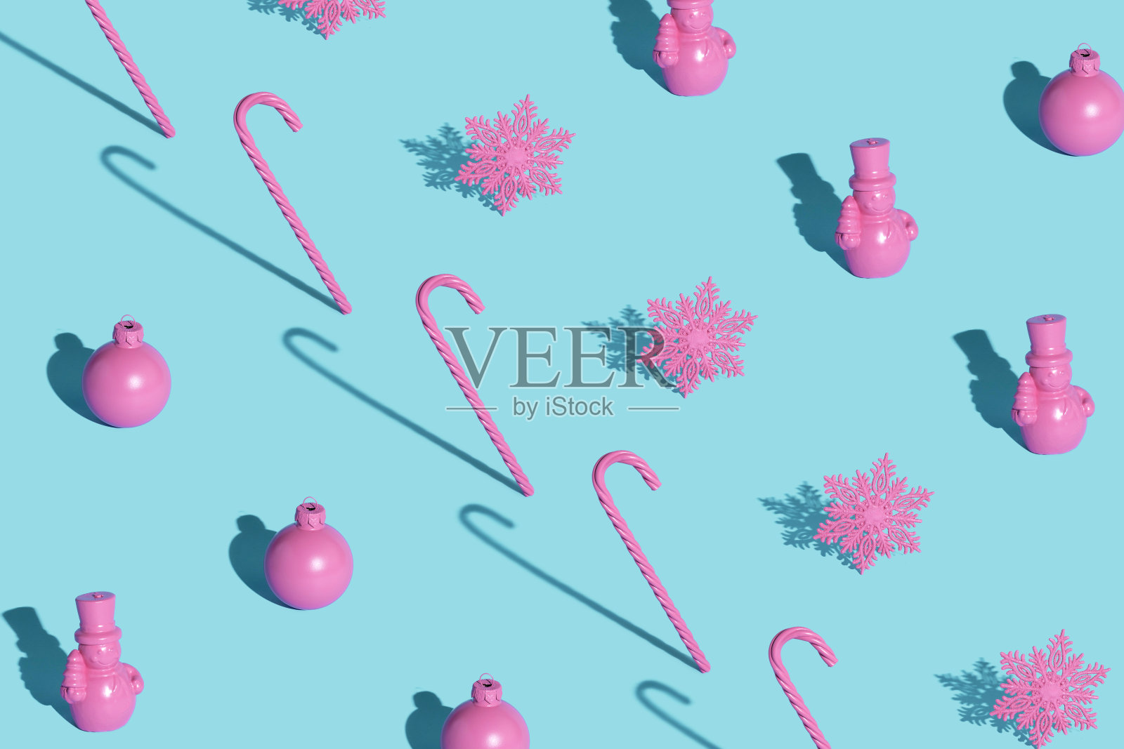 用粉红色的装饰品、糖果和雪花做成的现代圣诞图案,在柔和的蓝色背景上照片摄影图片