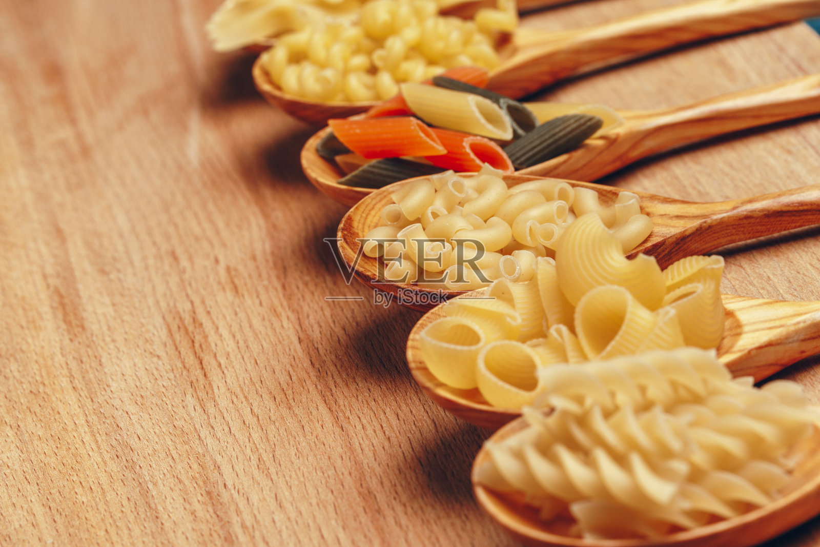 各种各样的意大利面放在勺子上。关闭了。有创意的照片。照片摄影图片