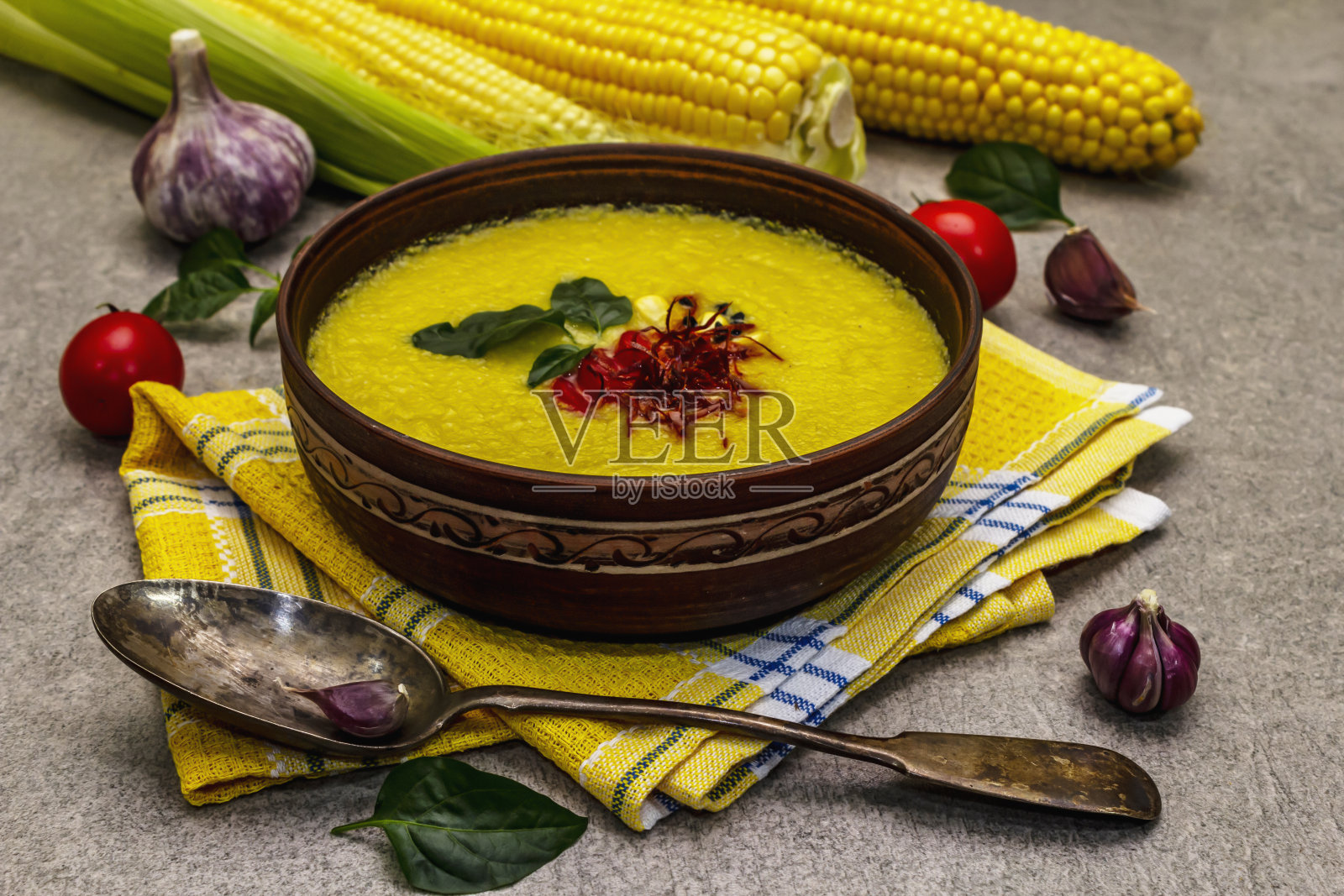 玉米奶油汤配新鲜蔬菜,香草和香料。经典的秋季热菜,石头混凝土背景照片摄影图片