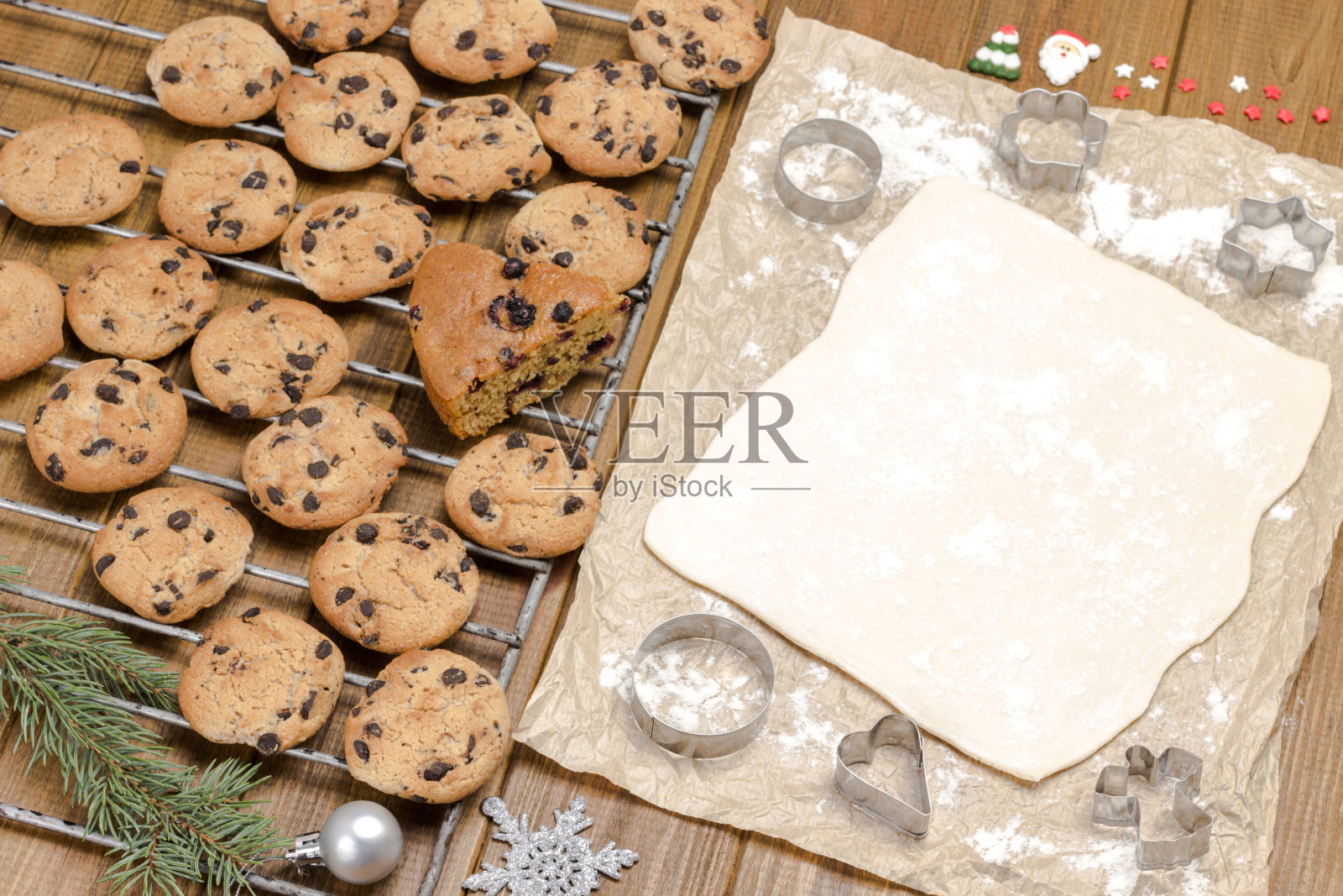 现成的饼干和冷杉树枝。在纸上烤饼干用的面团。照片摄影图片