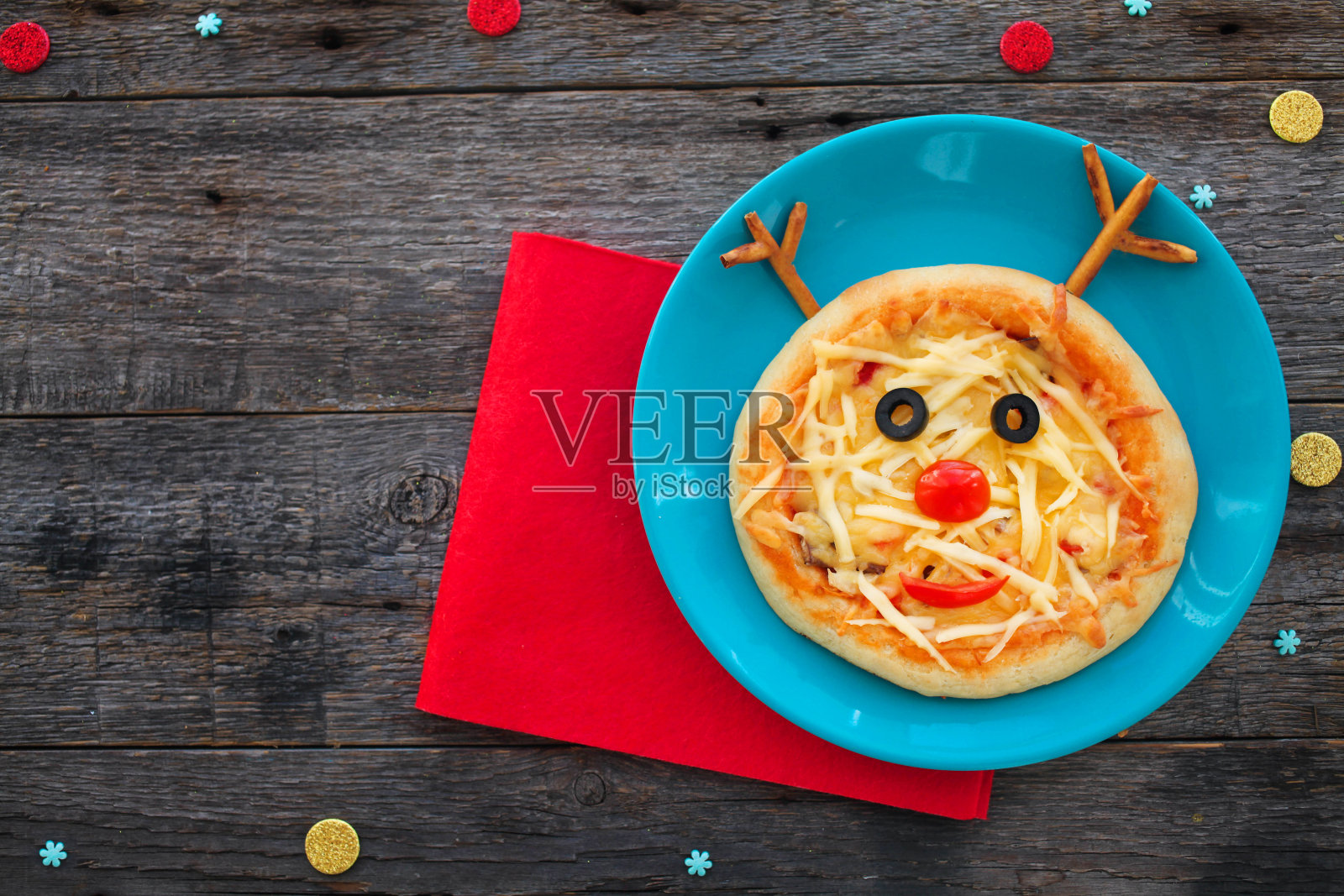 以木头为背景的驯鹿形状的圣诞披萨。副本的空间。给孩子们的有趣的食物-可爱的鹿。照片摄影图片